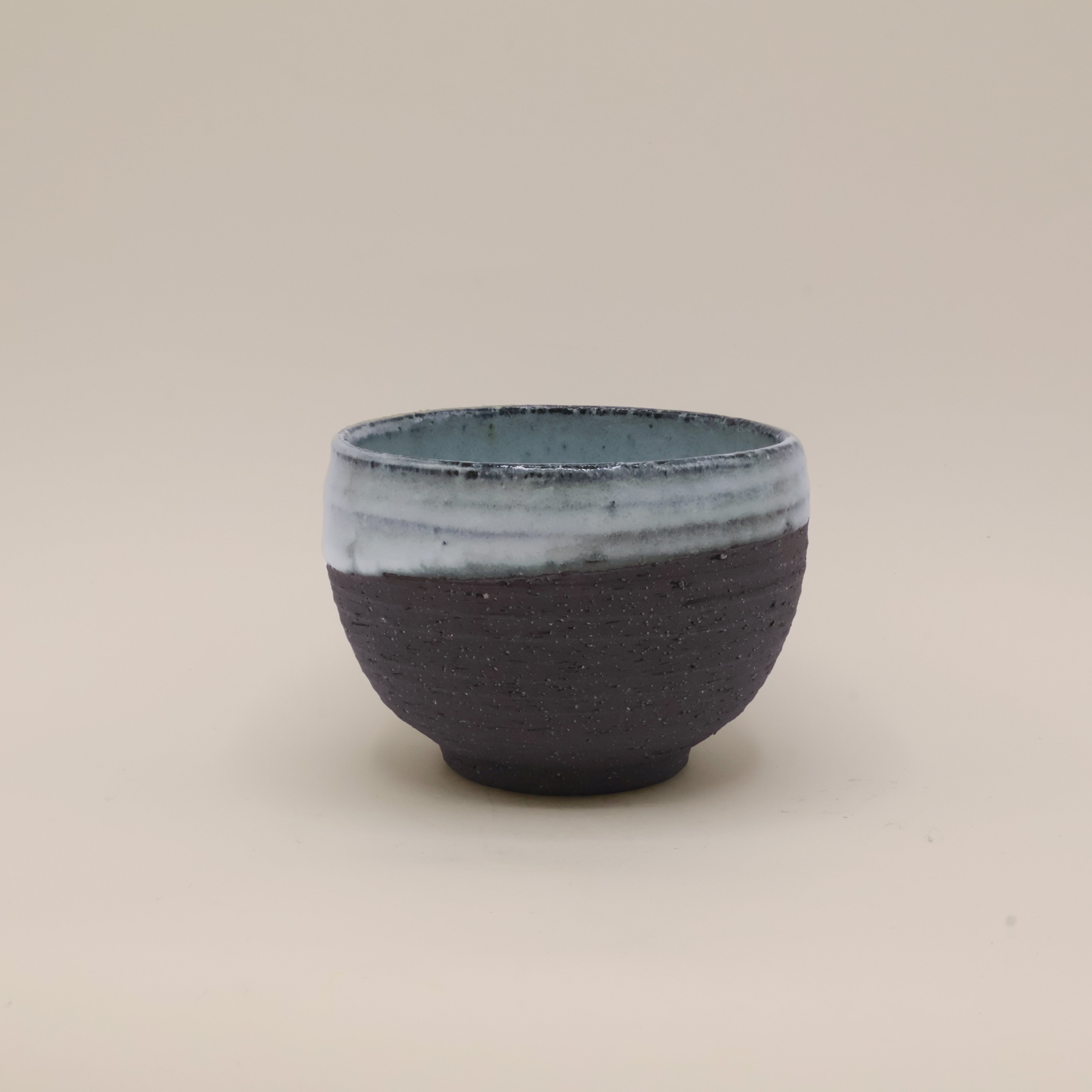 Sort kop med rustik overflade og blå glasur