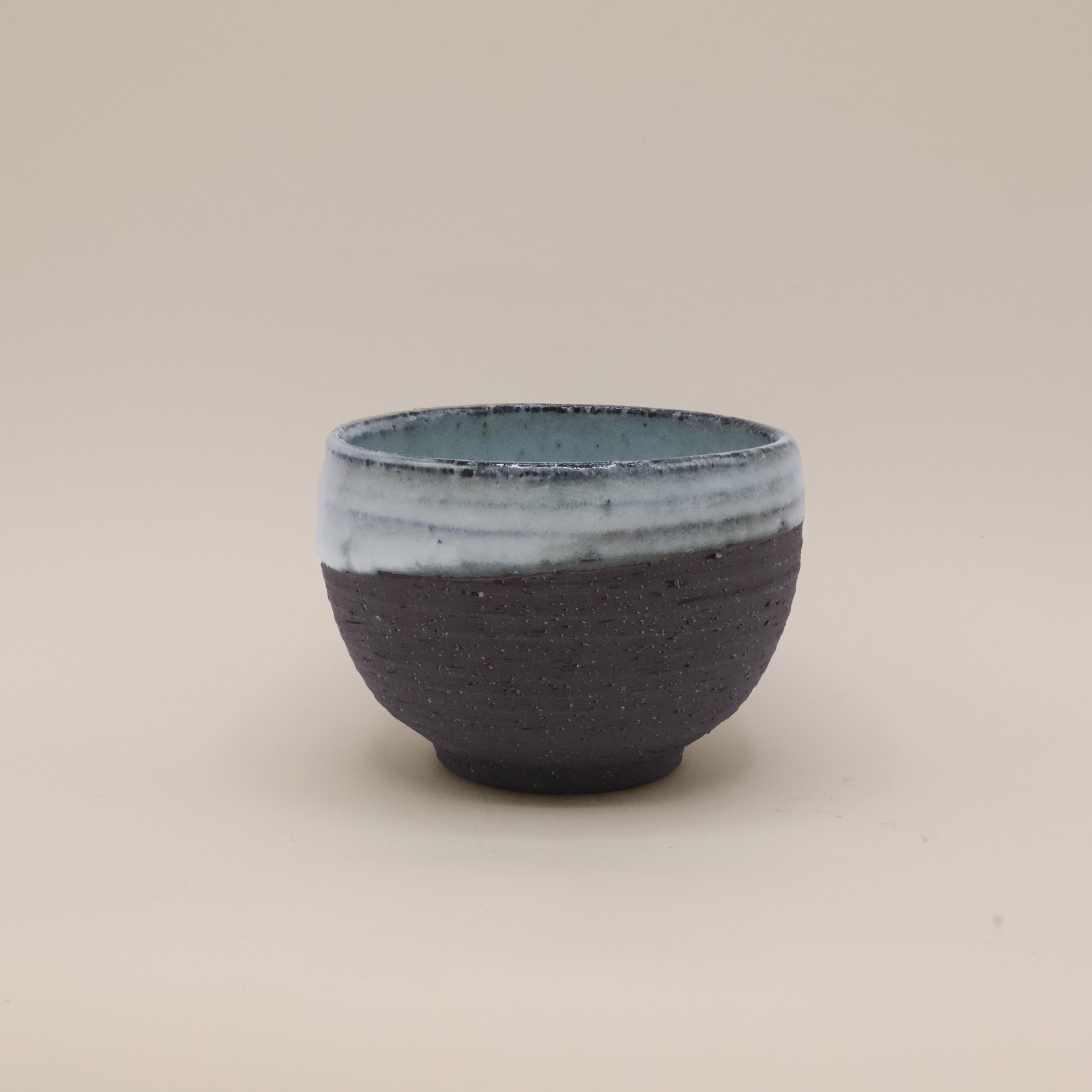 Sort kop med rustik overflade og blå glasur