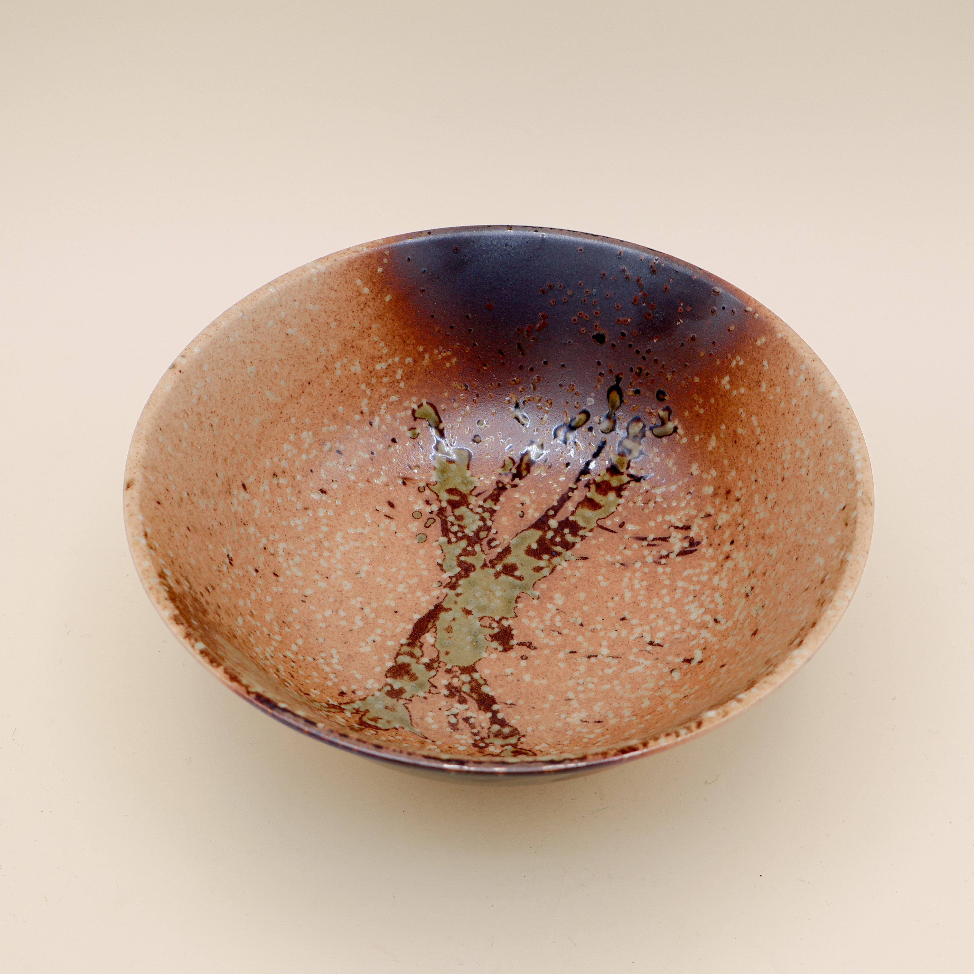 Ramen bowl in orange/brown with metallic detail and green splash