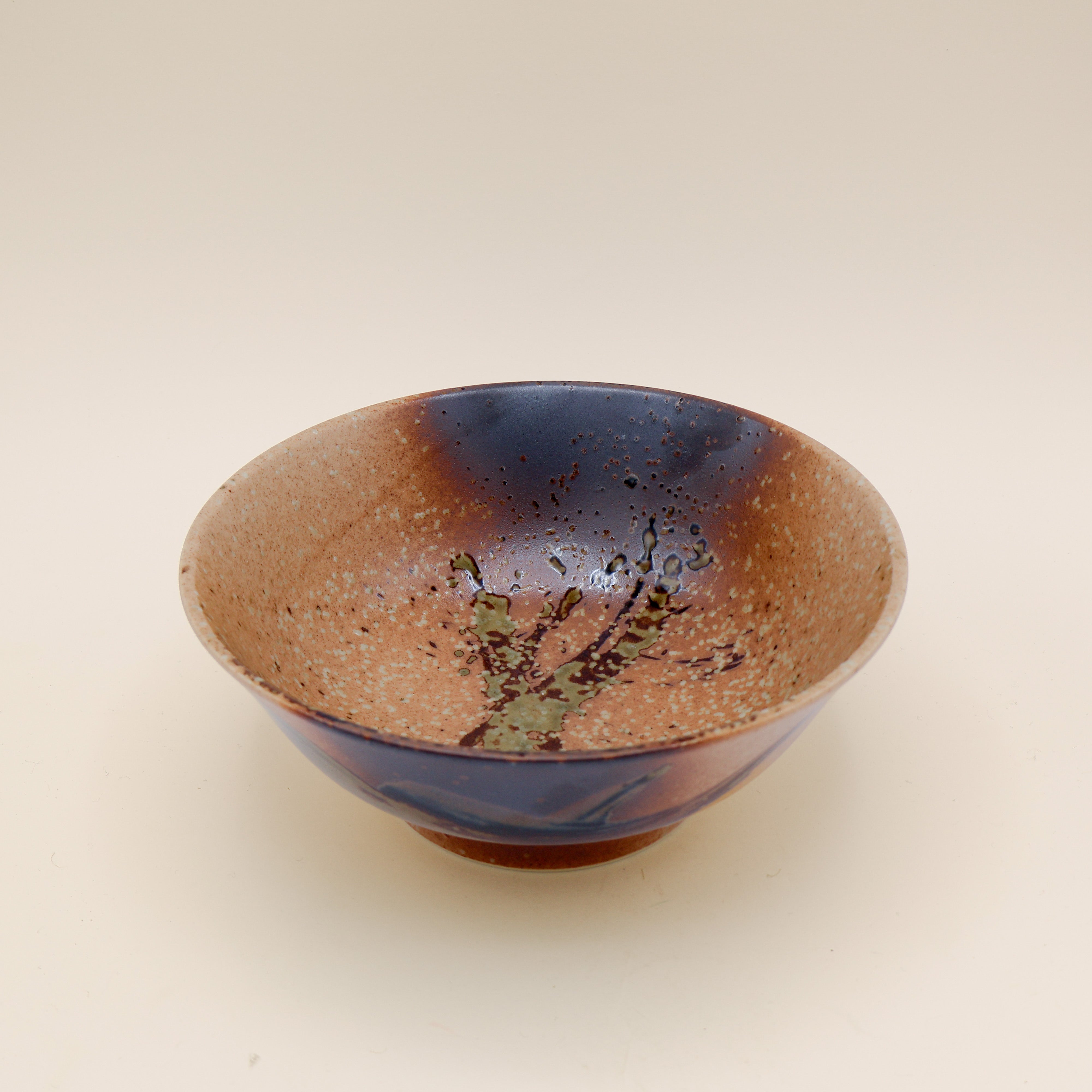 Ramen bowl in orange/brown with metallic detail and green splash