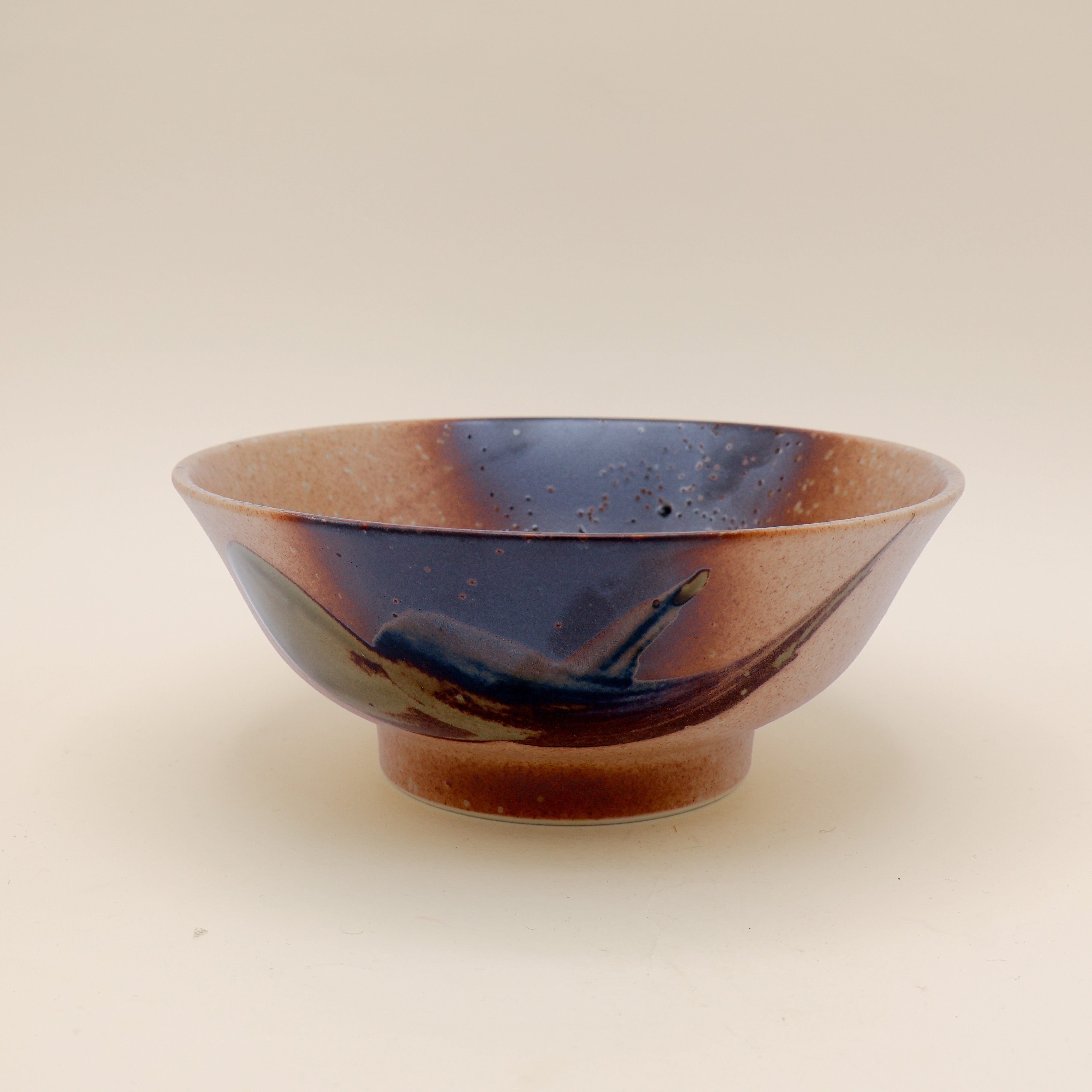Ramen bowl in orange/brown with metallic detail and green splash