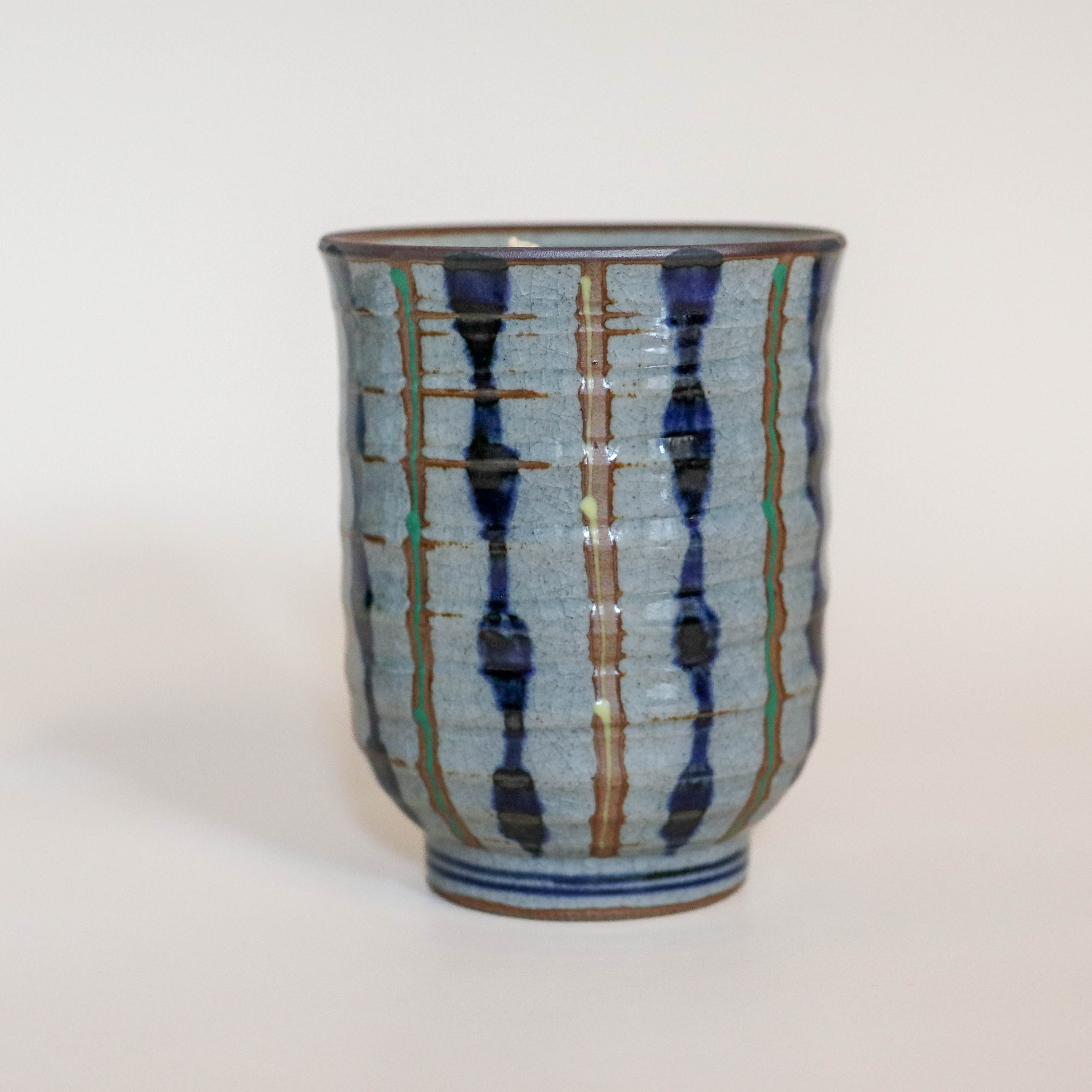 Grå kop med blå, gule og grønne striber