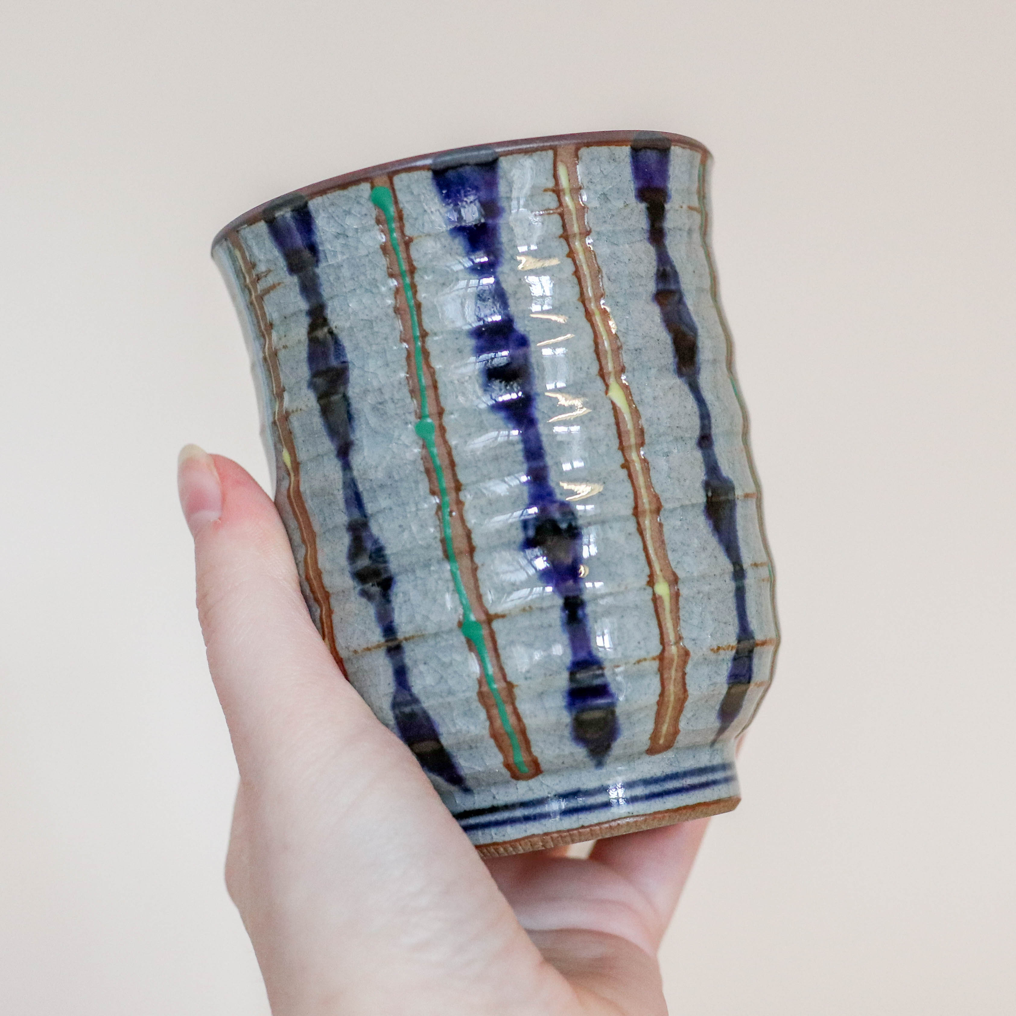 Grå kop med blå, gule og grønne striber