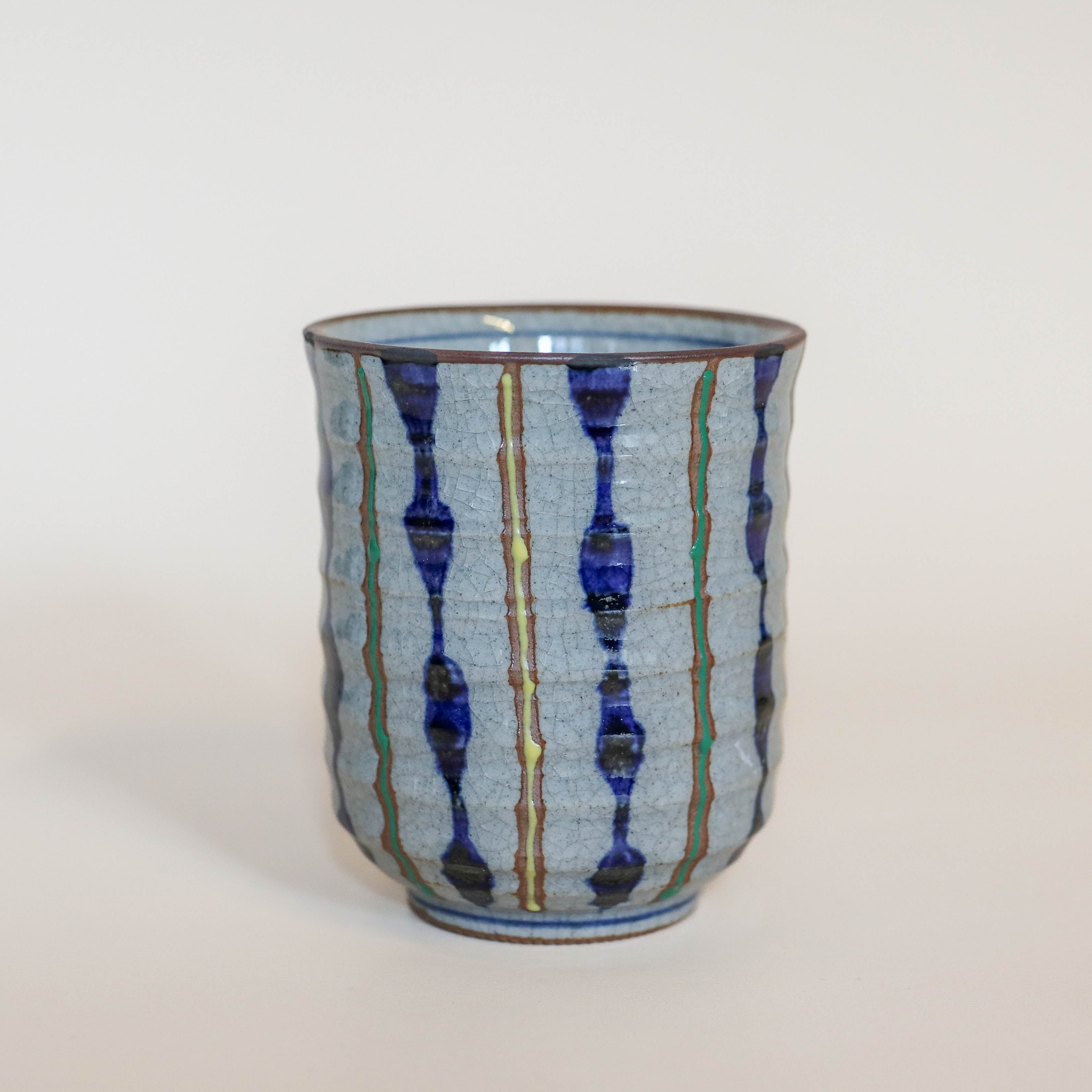 Grå kop med blå, gule og grønne striber