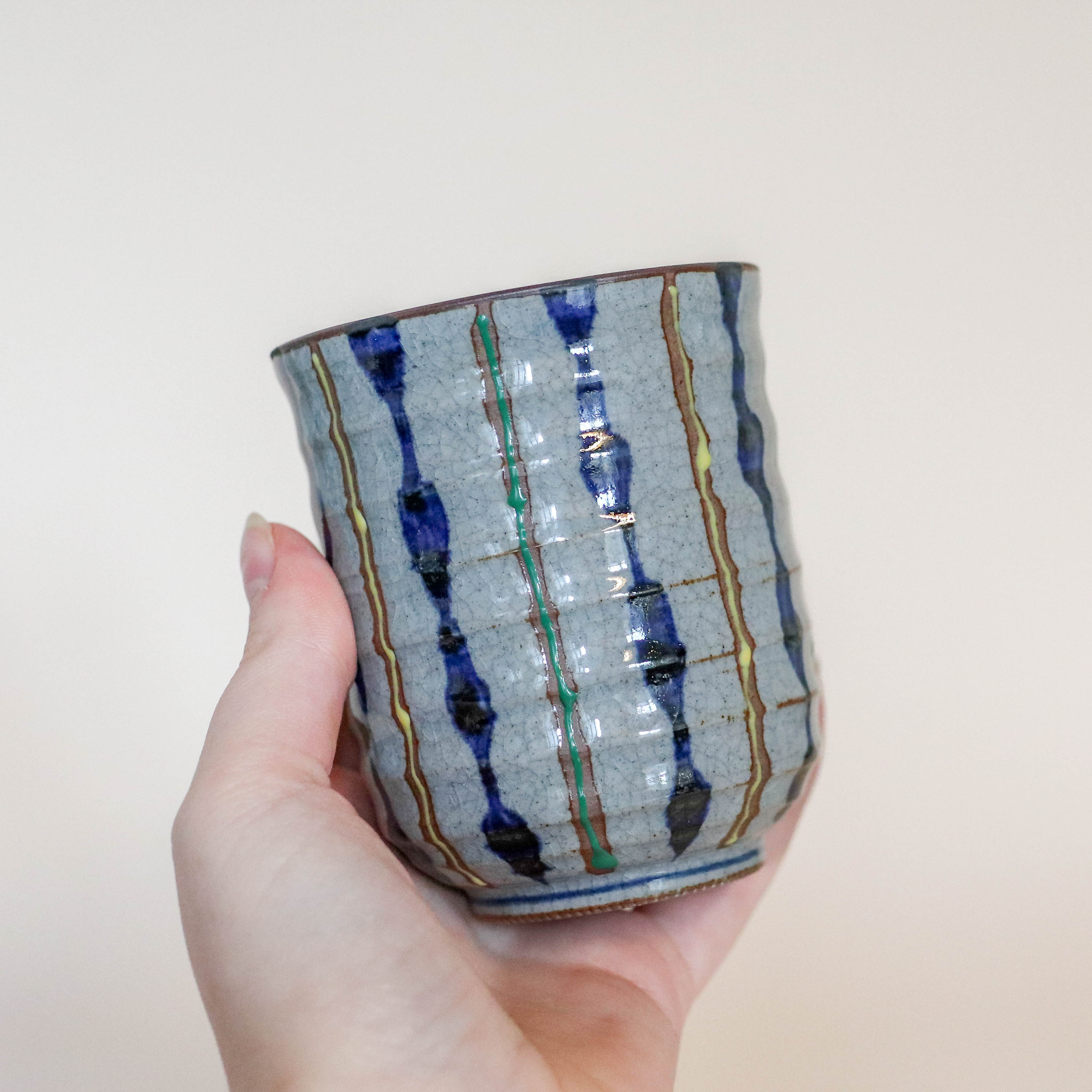 Grå kop med blå, gule og grønne striber