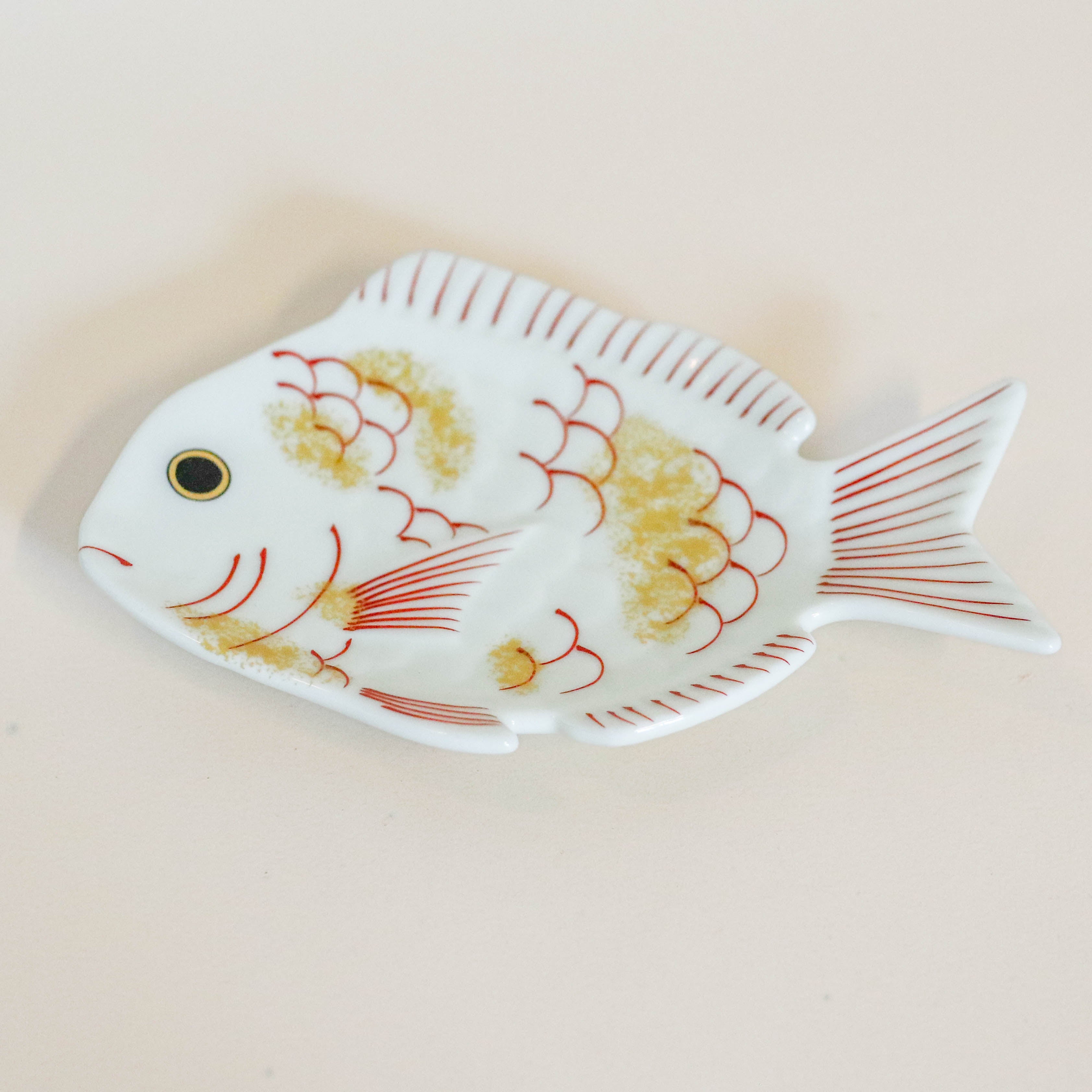 Tallerken formet som fisk med gulddetaljer