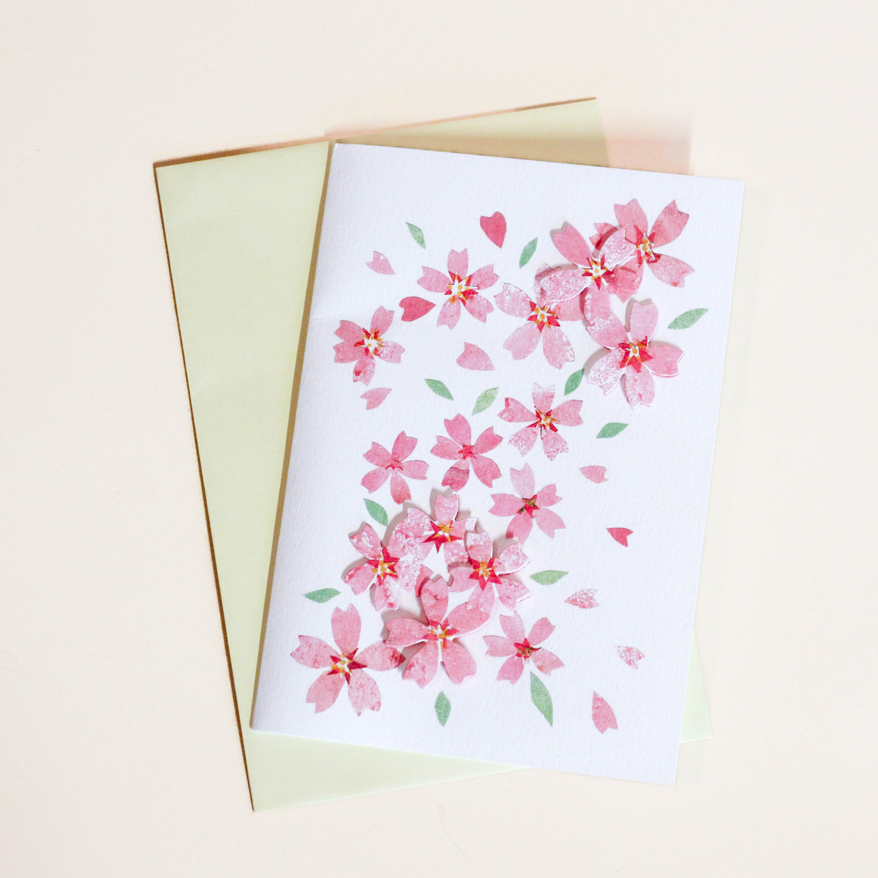 Kort med lyserøde sakura blomster og lysegul kuvert