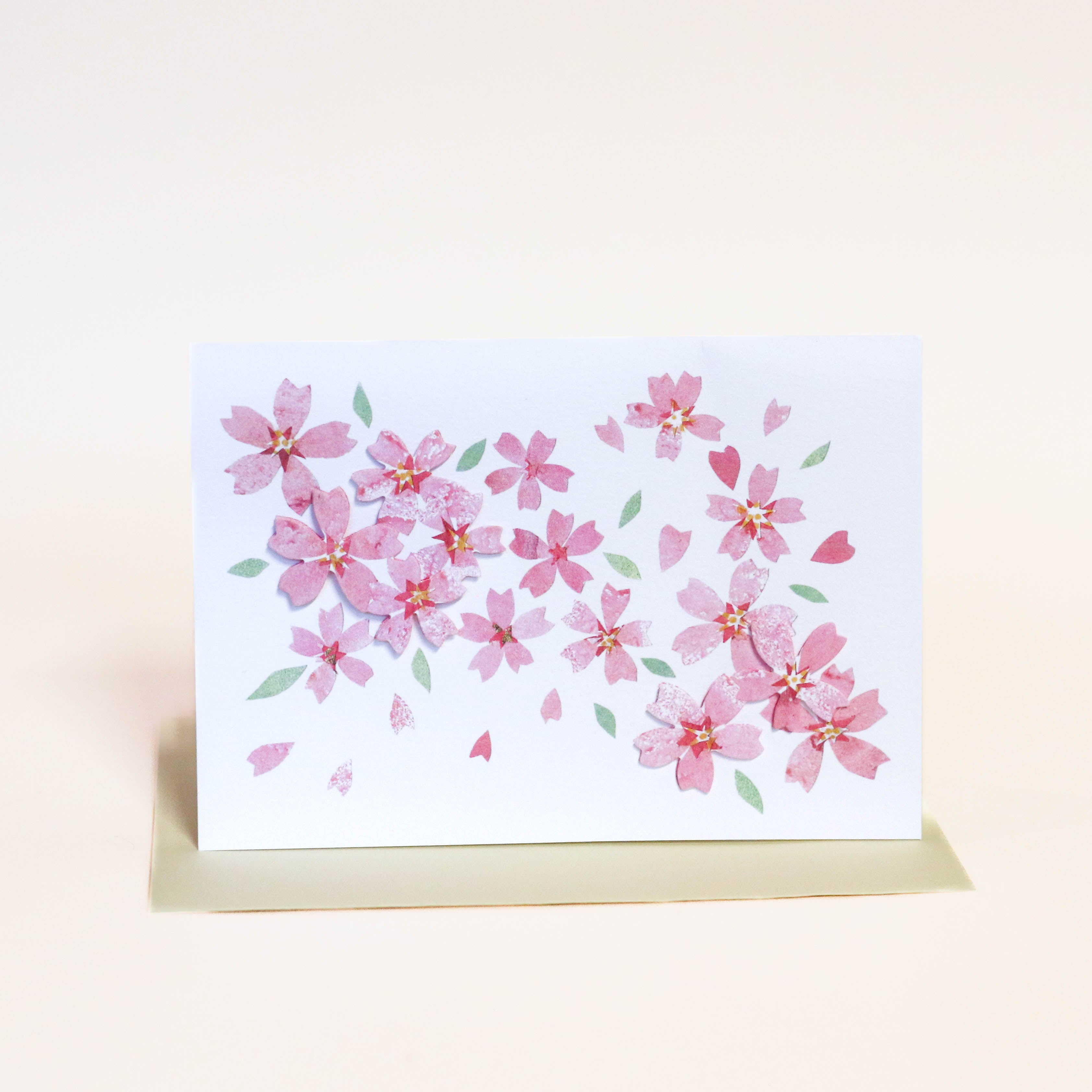 Kort med lyserøde sakura blomster og lysegul kuvert