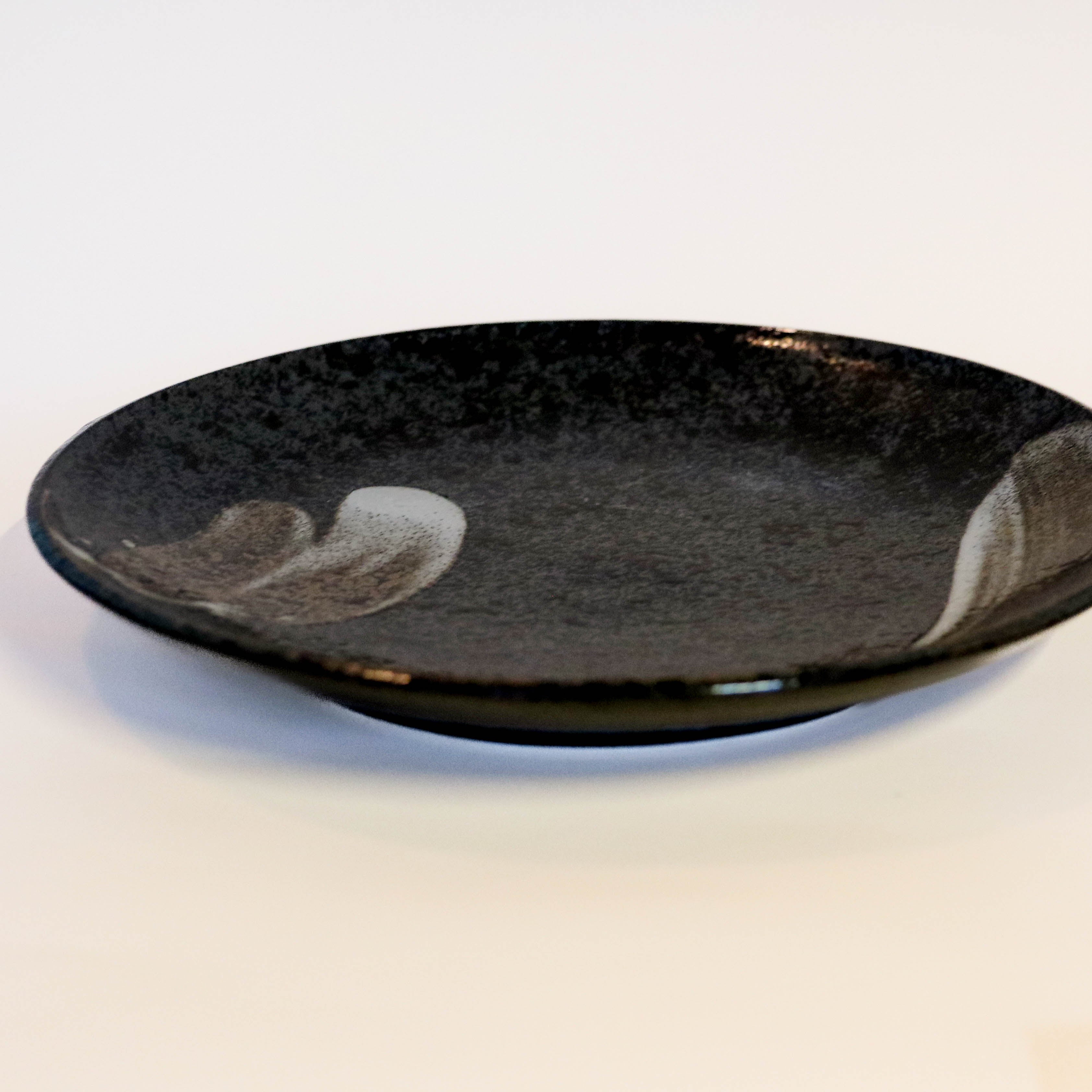 Stort fad i mørke nuancer med hvide penselstrøg