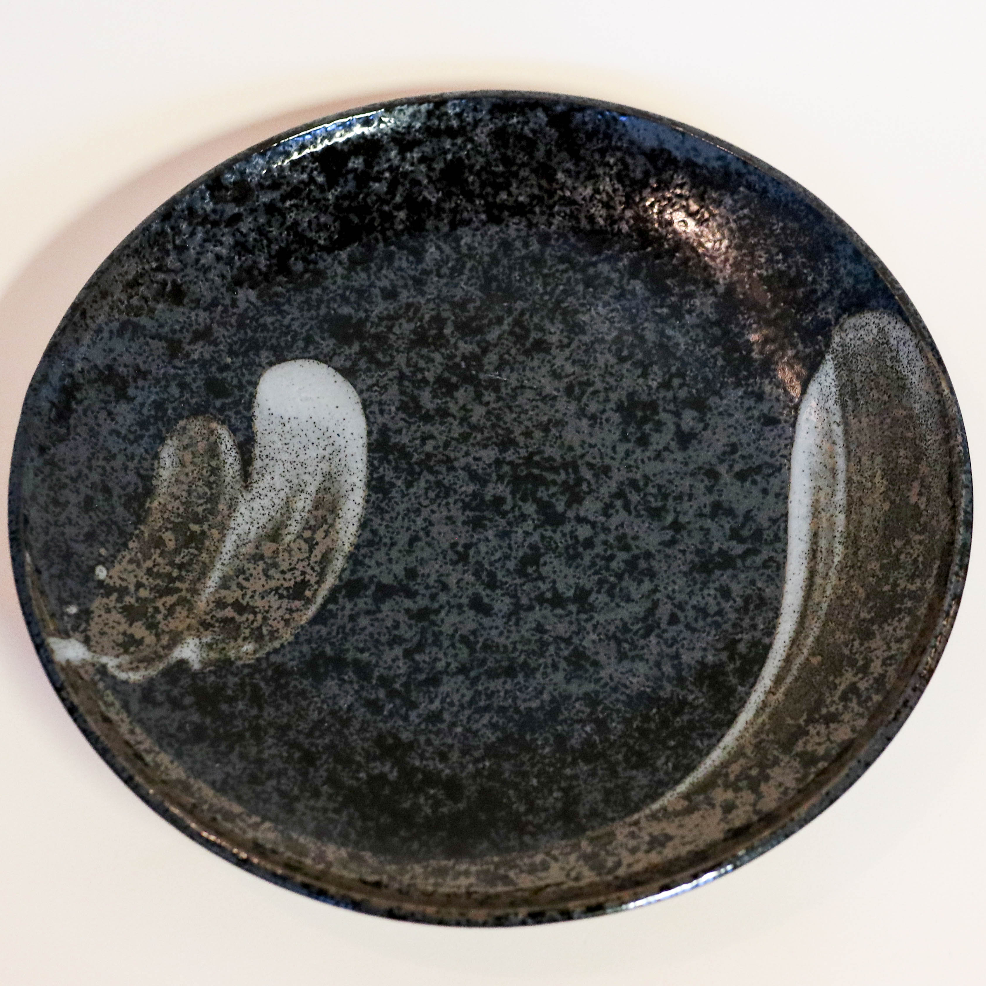 Stort fad i mørke nuancer med hvide penselstrøg