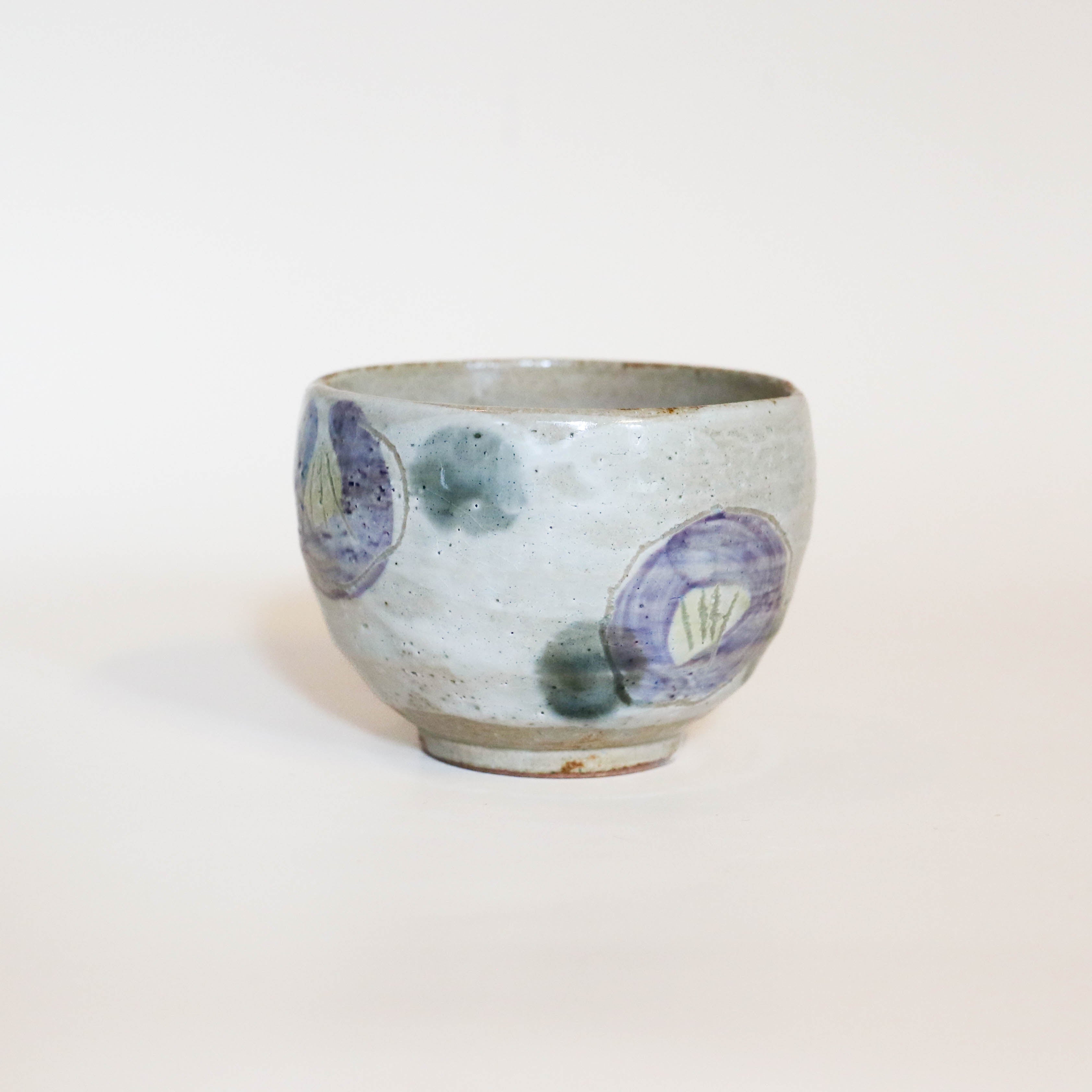 Kop med lilla blomster og grønne prikker