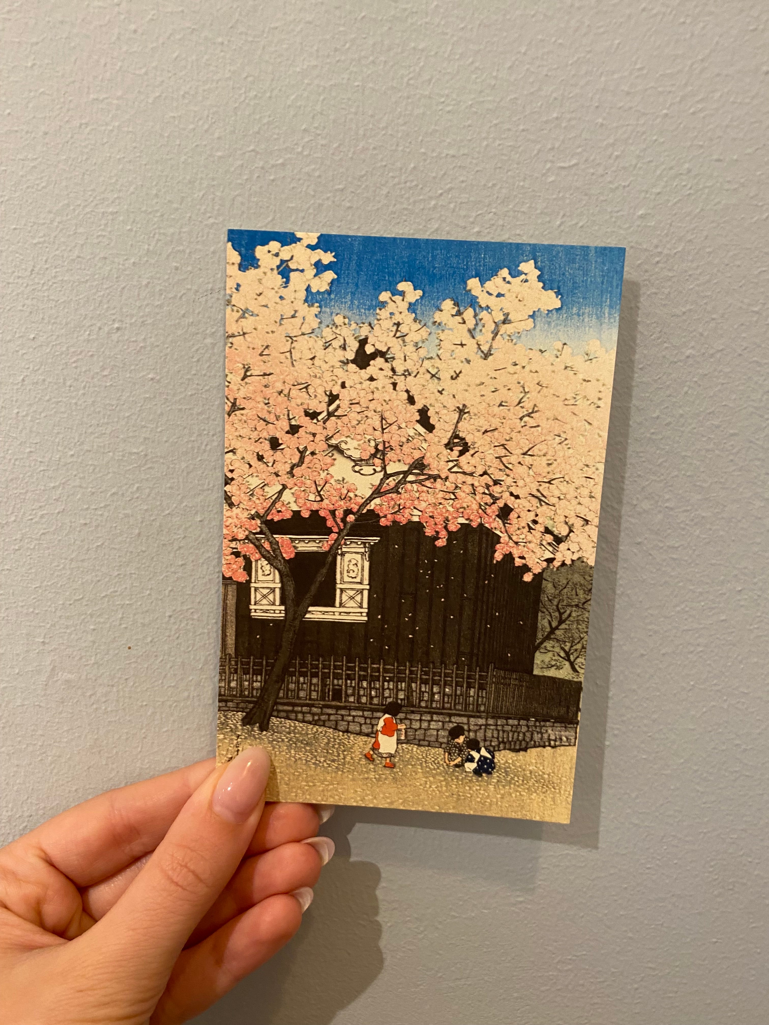Kort med legende børn foran japansk hus og sakuratræ