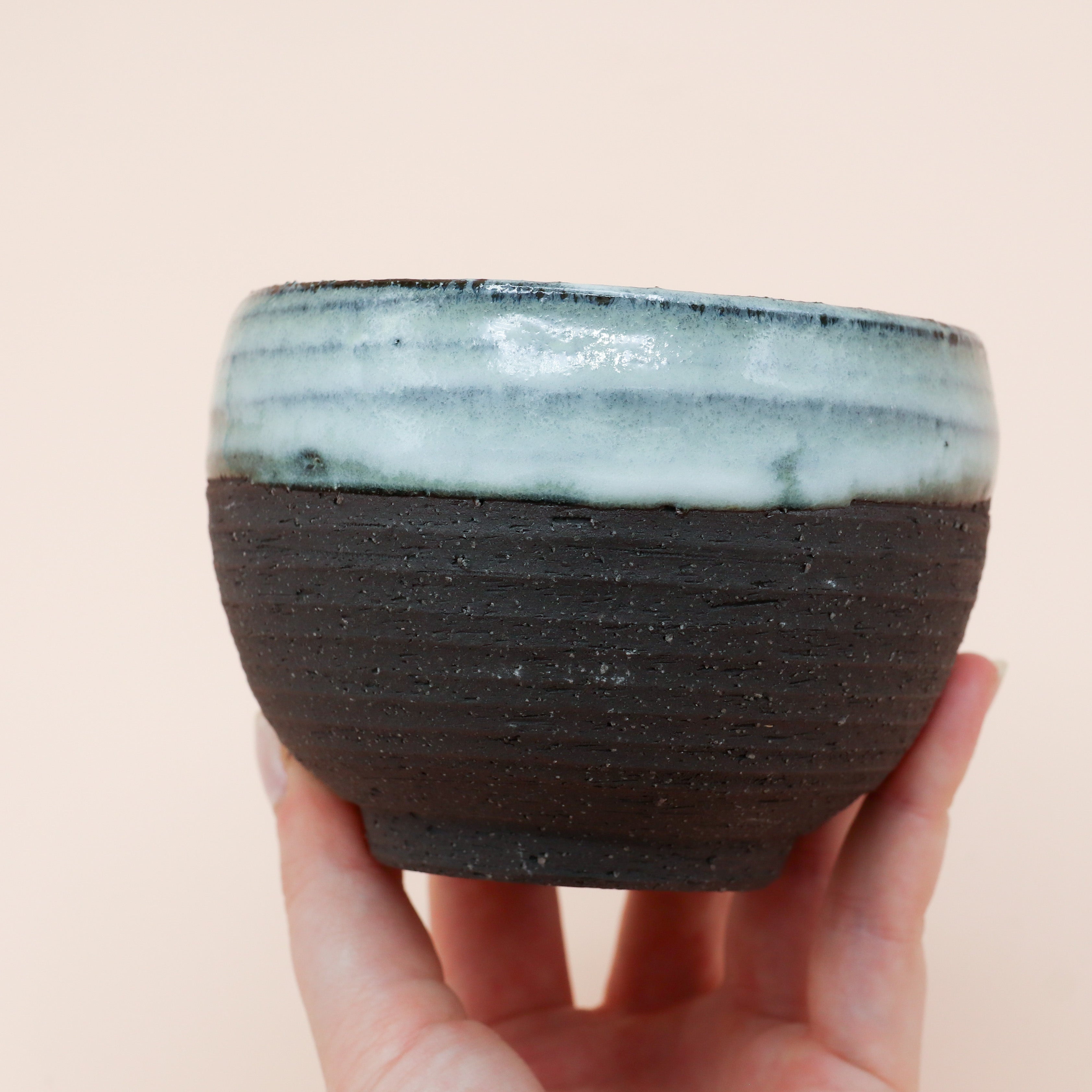 Sort kop med rustik overflade og blå glasur