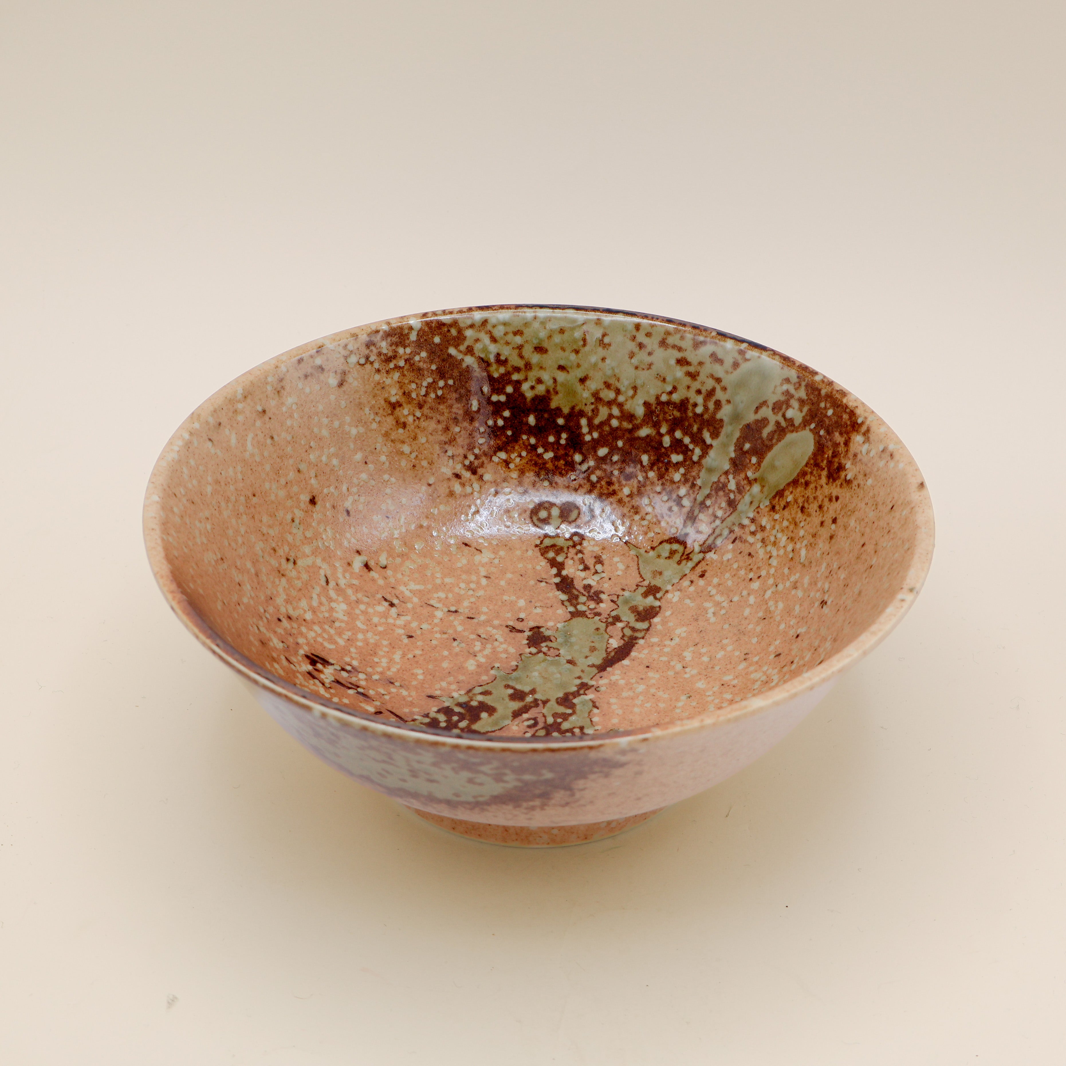 Ramen bowl in orange/brown with metallic detail and green splash