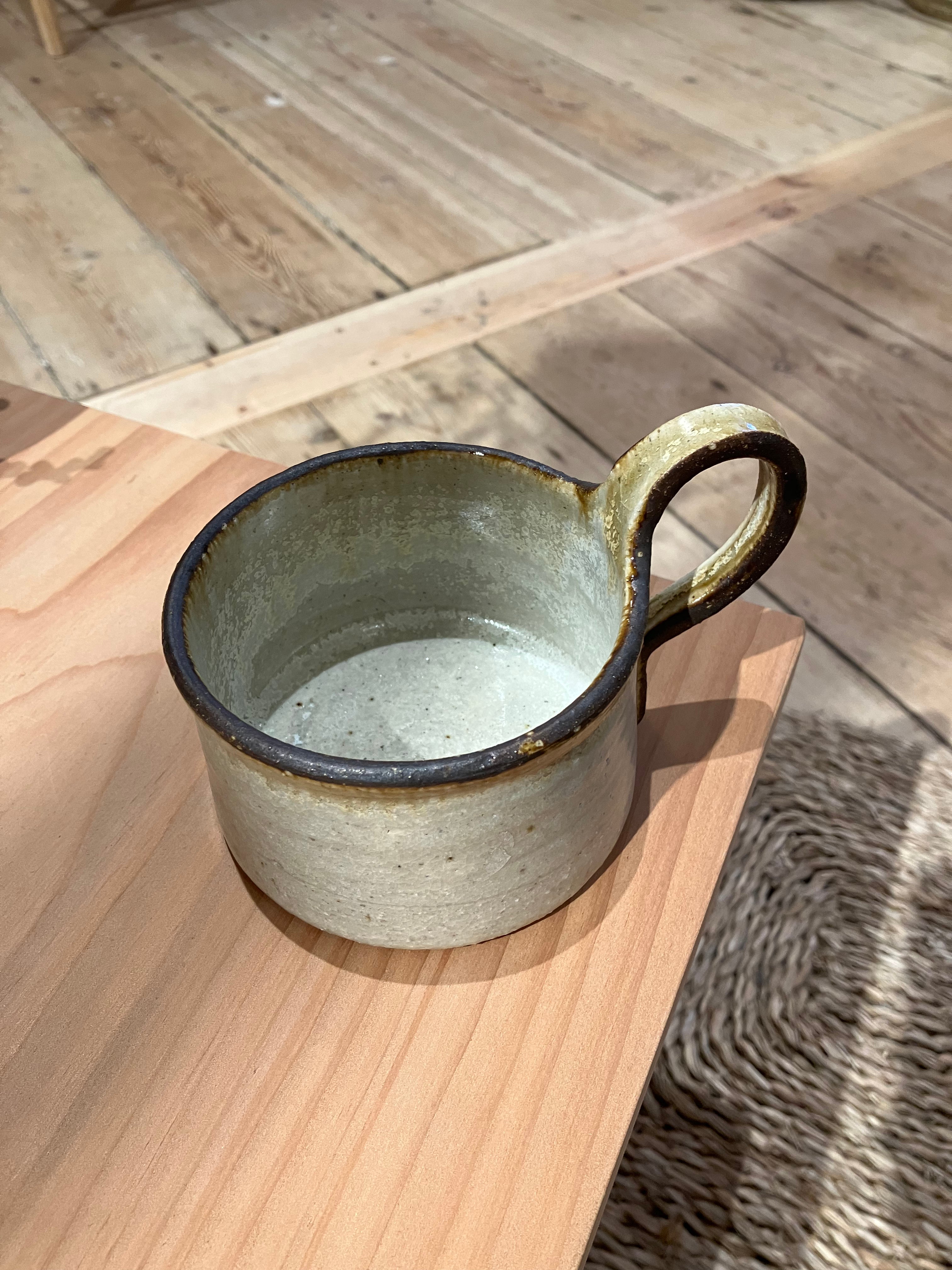 Rustic cup with brown rim and handle