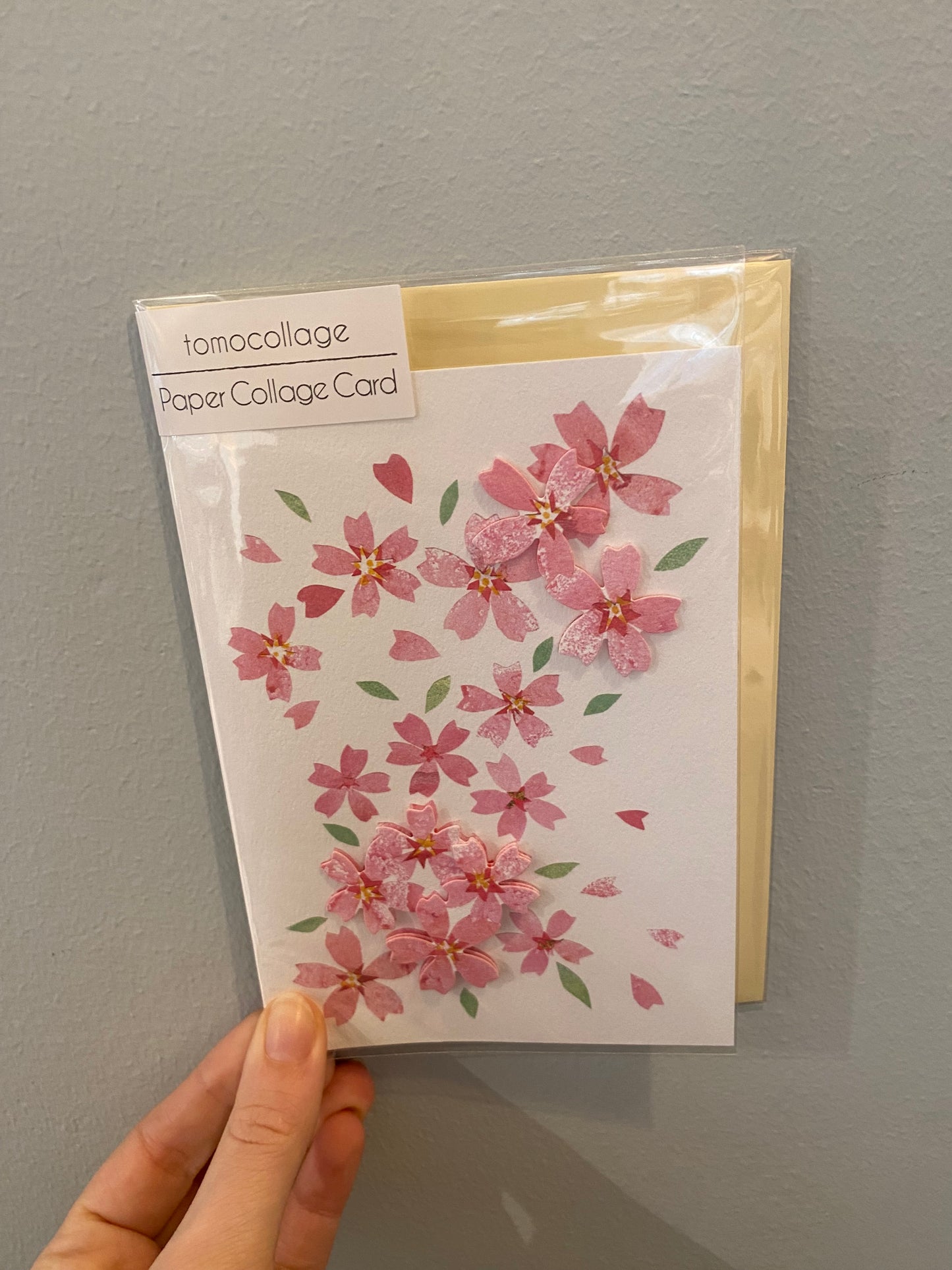 Kort med lyserøde sakura blomster og lysegul kuvert