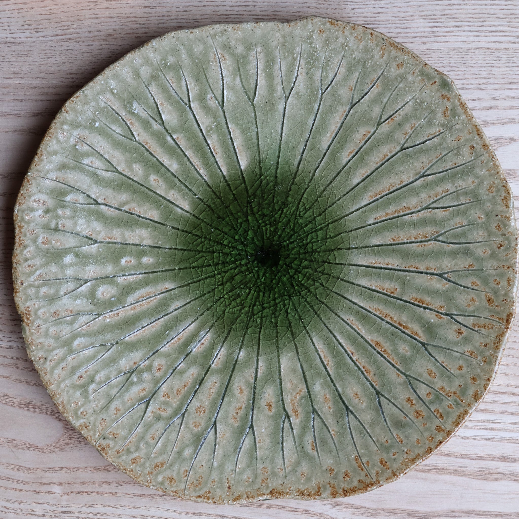 Stort rundt fad med grønt bladmønster