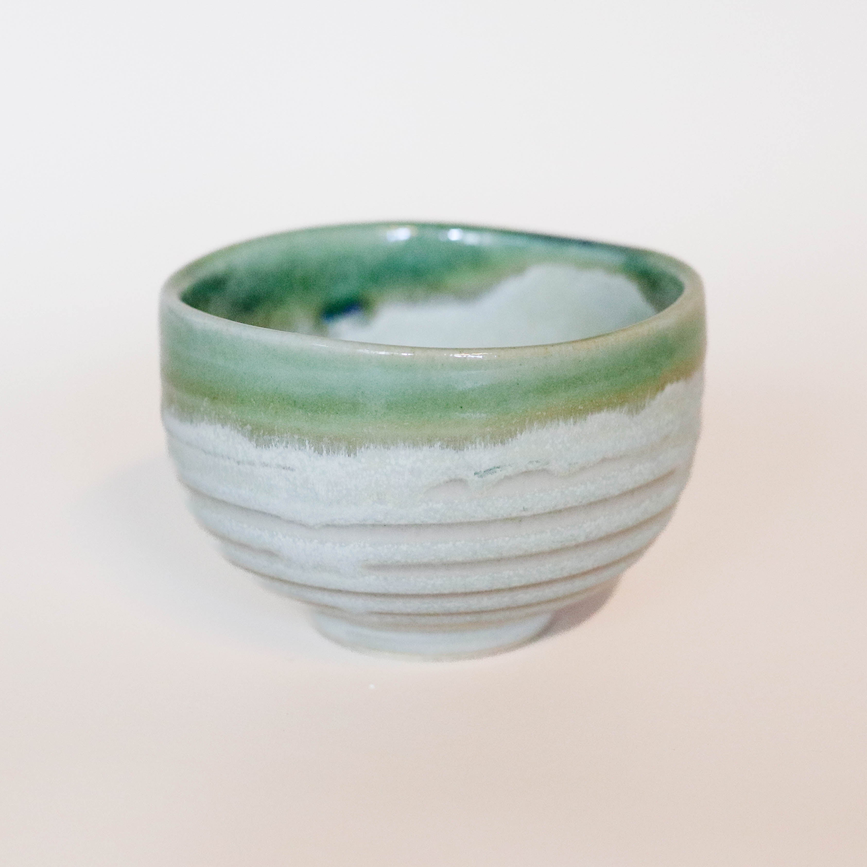 Sand colored cup with green rim