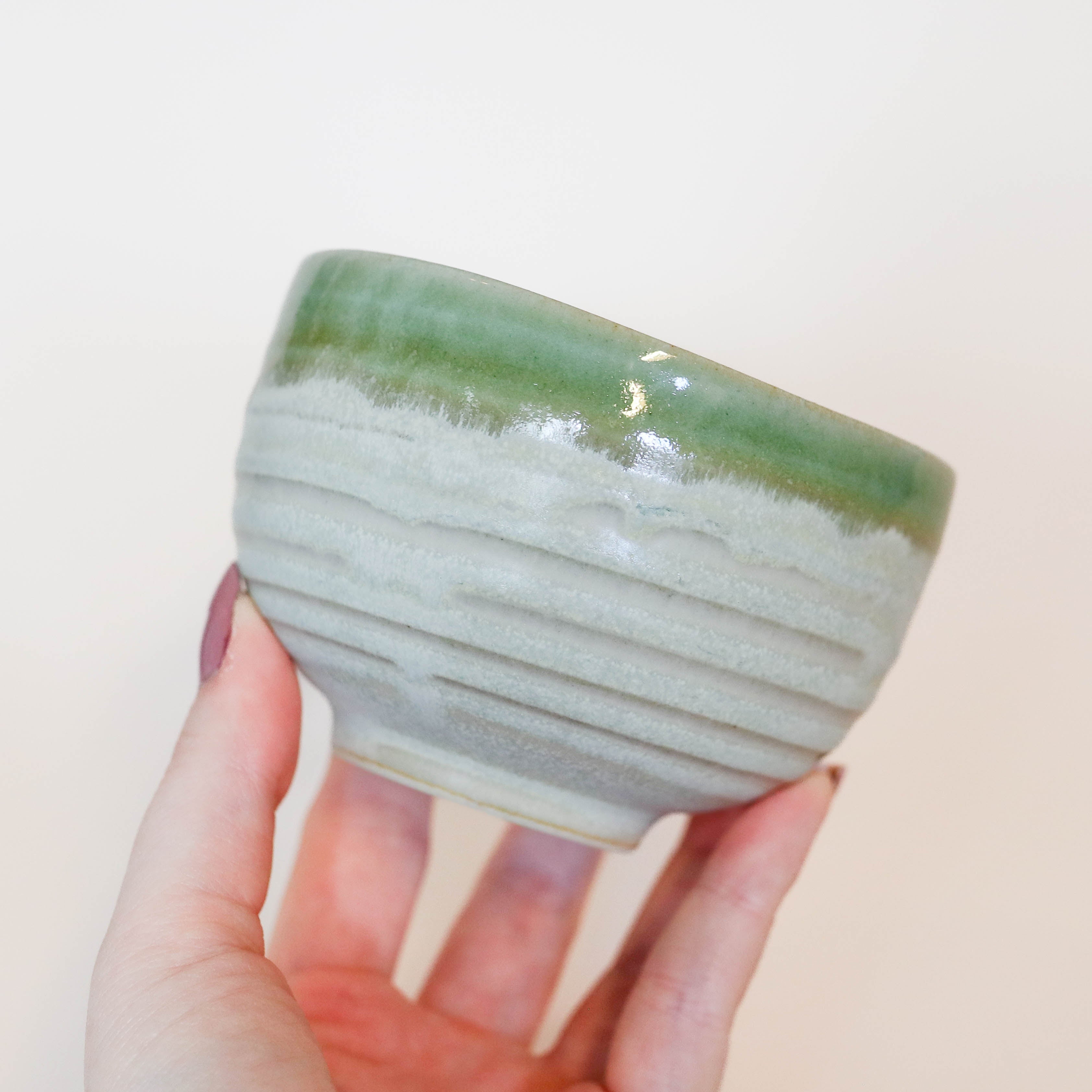 Sand colored cup with green rim