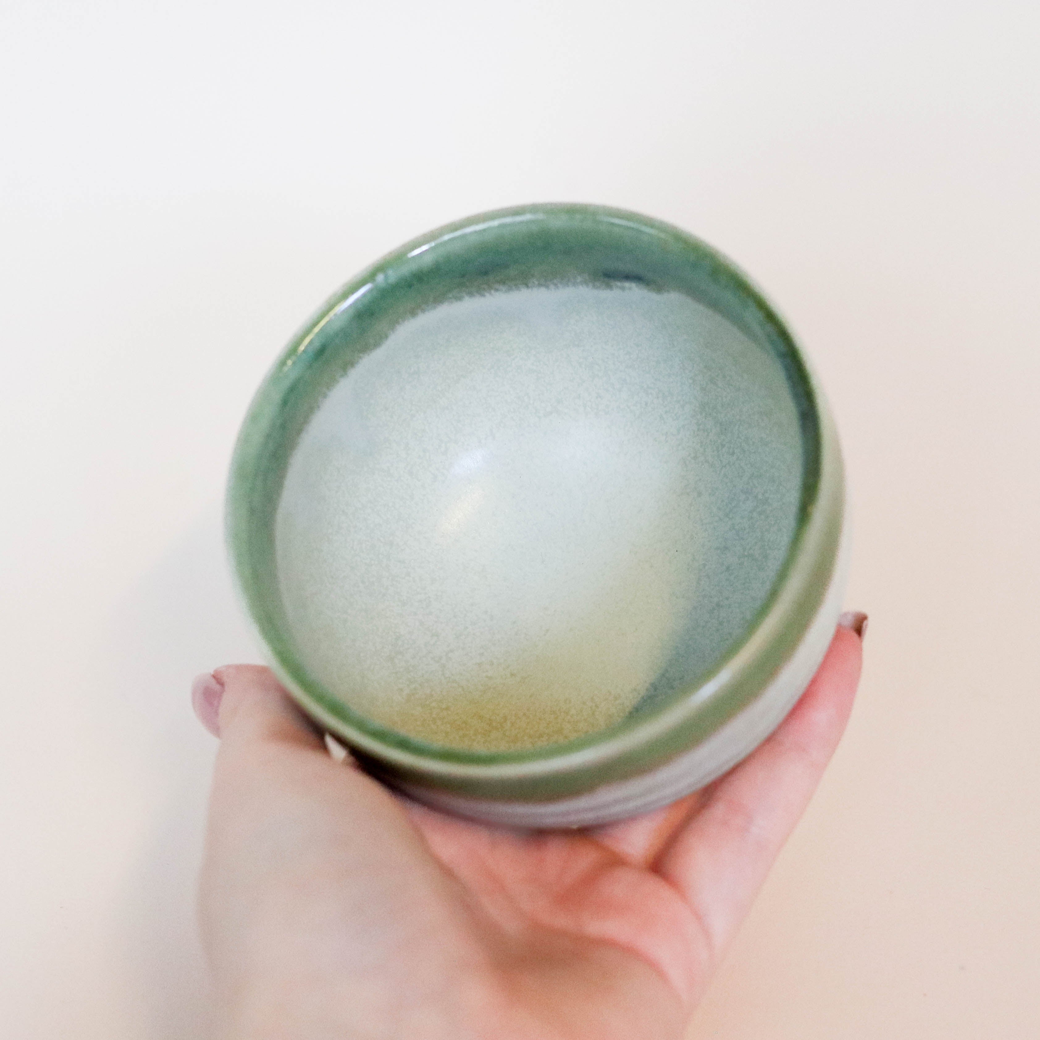Sand colored cup with green rim