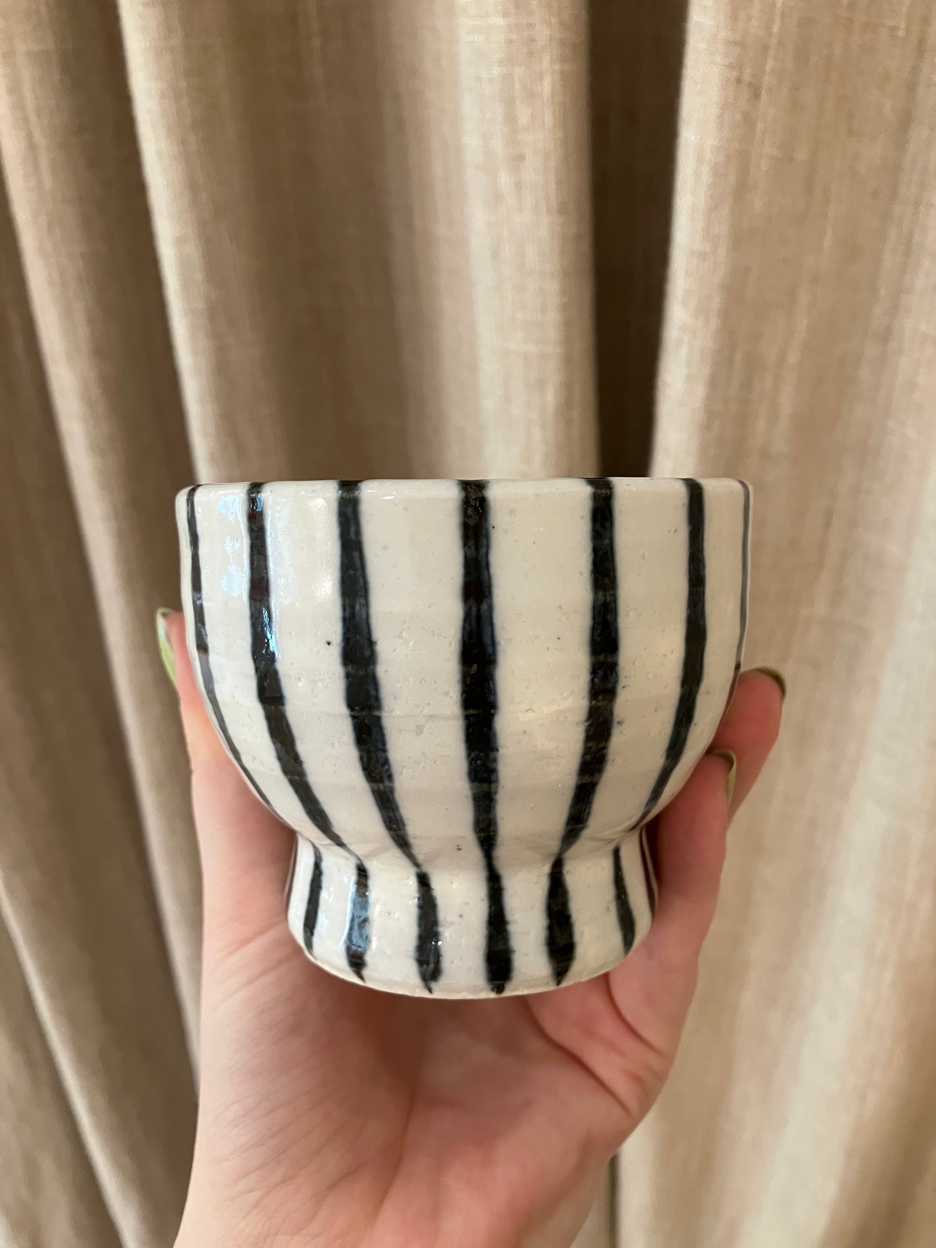 Handmade ceramic cup on foot with dark blue stripes