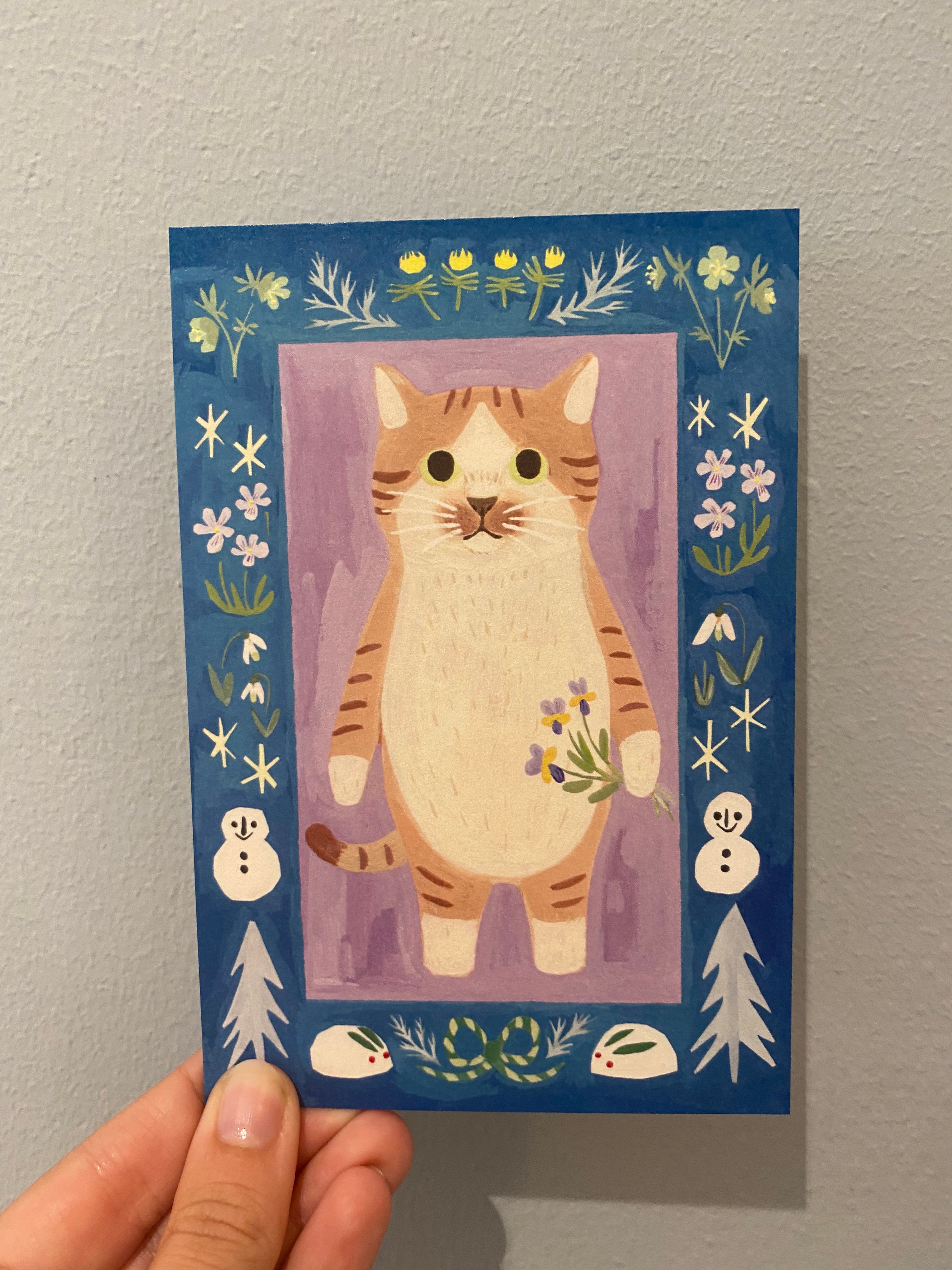 Japanese card blue background with motif of cat holding purple flowers