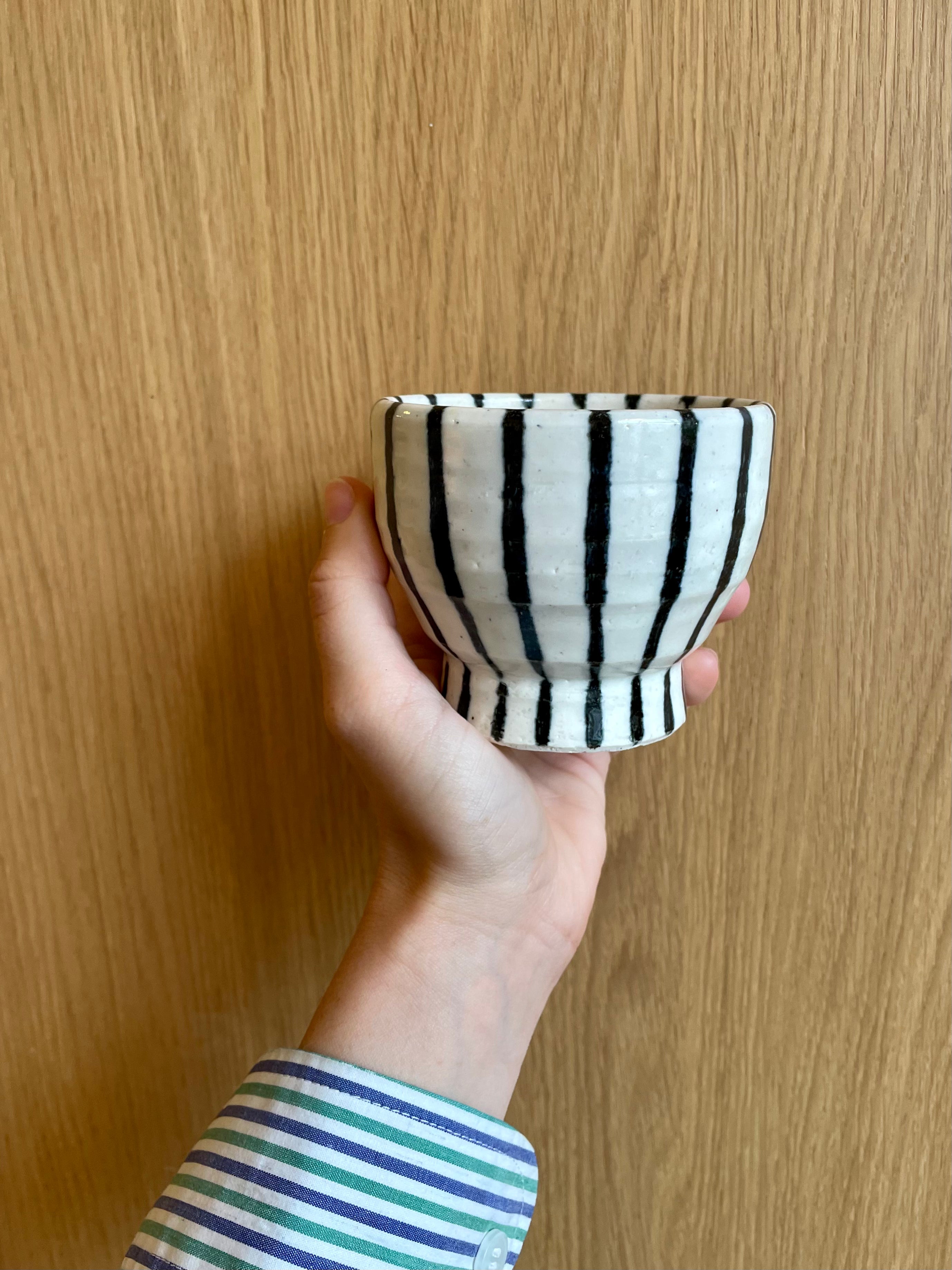 Handmade ceramic cup on foot with dark blue stripes