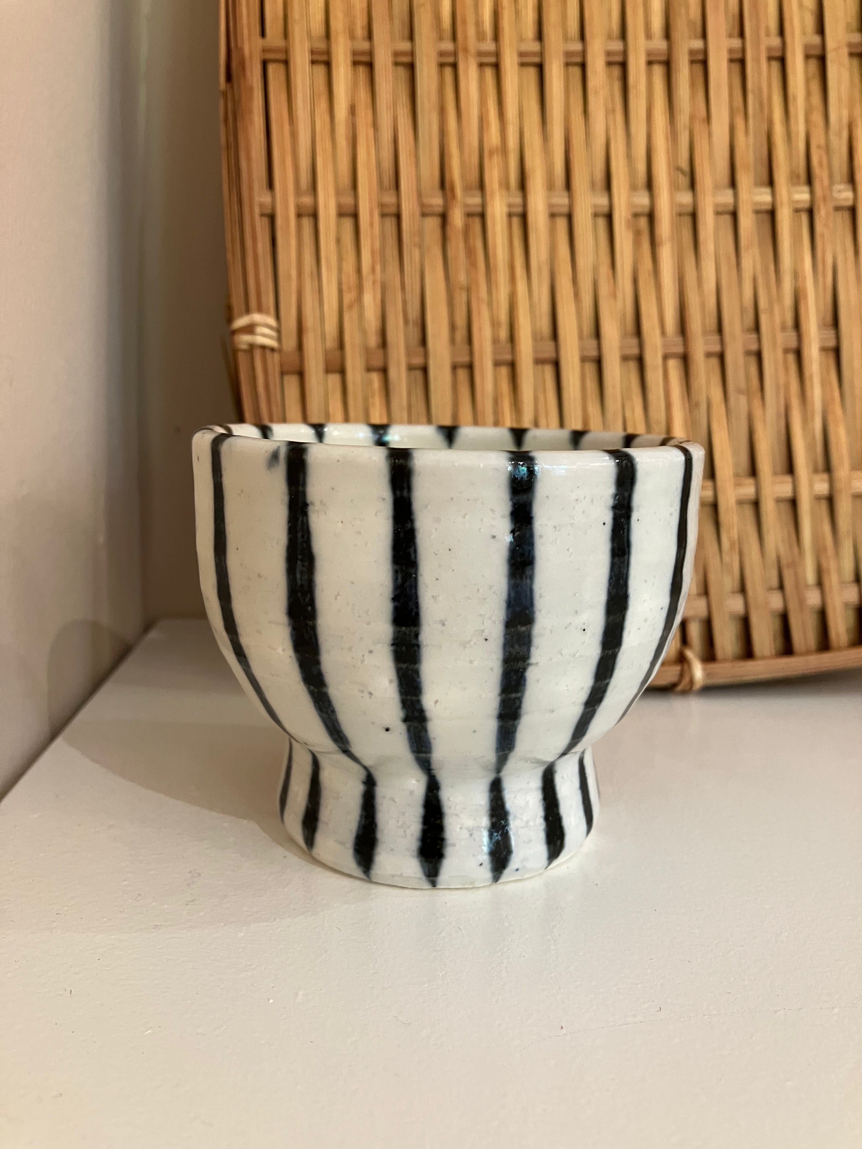 Handmade ceramic cup on foot with dark blue stripes