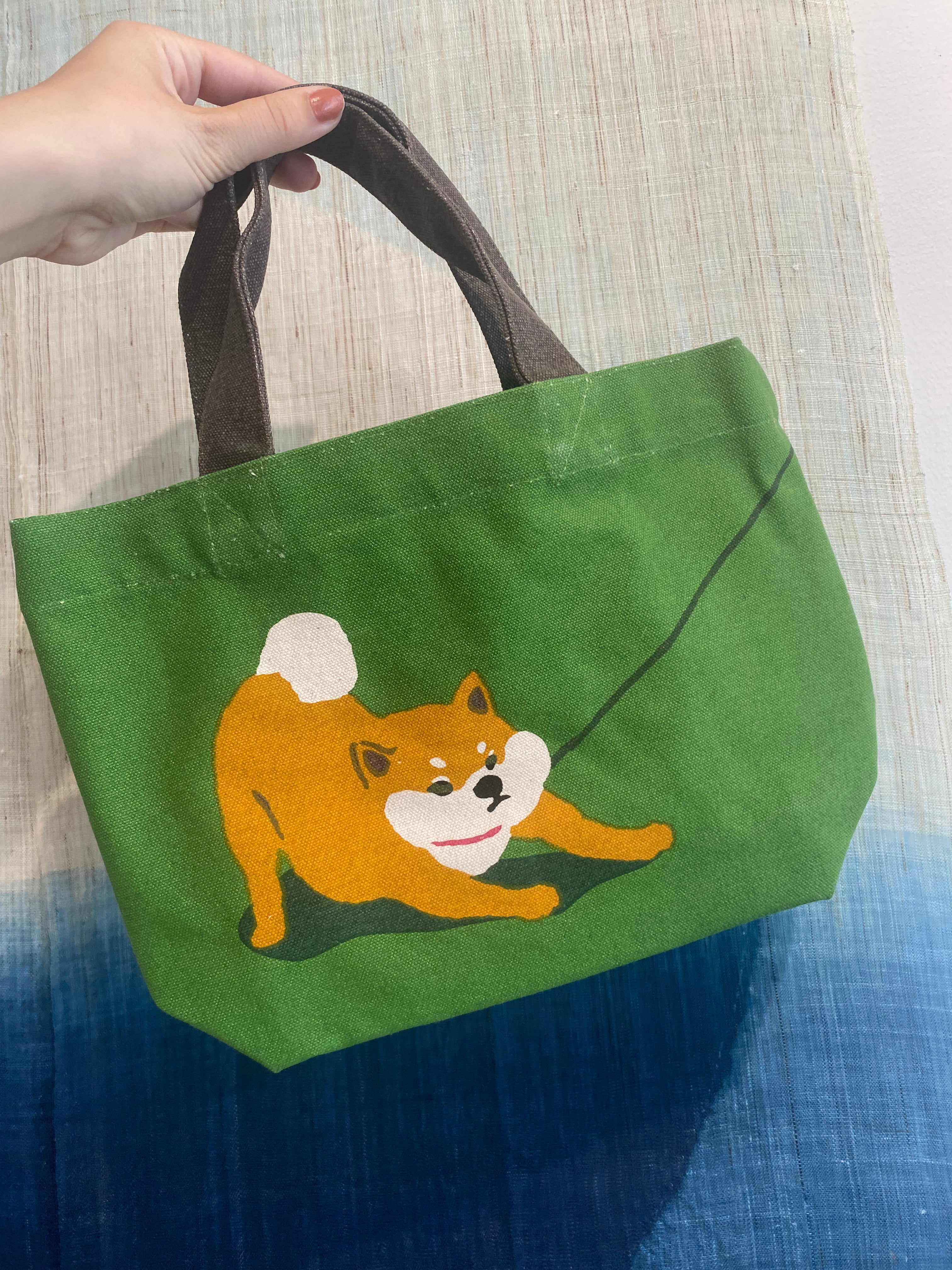 Small green bag with a stubborn shiba that pulls on a leash