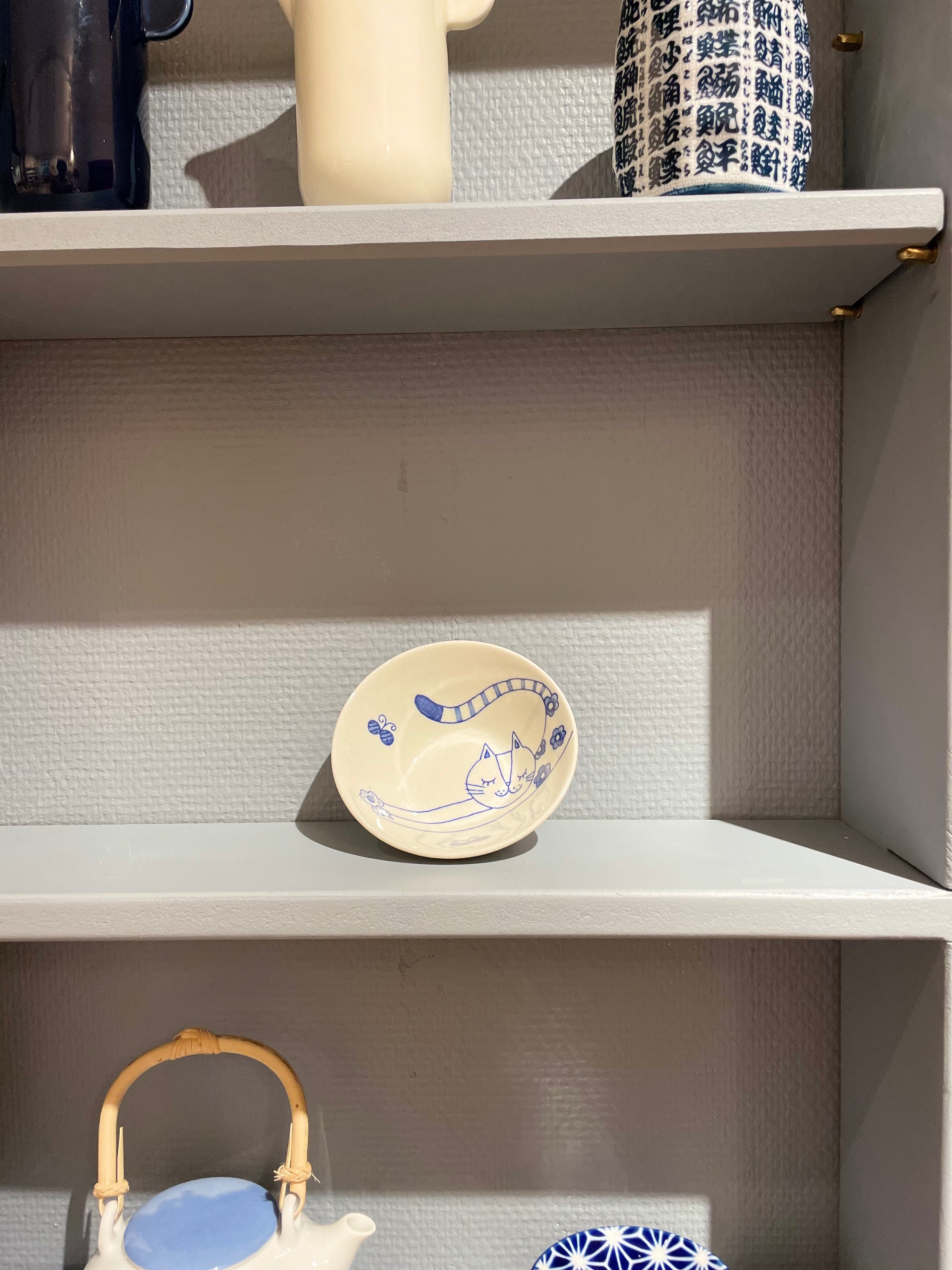 Small white bowl with blue cat stretching