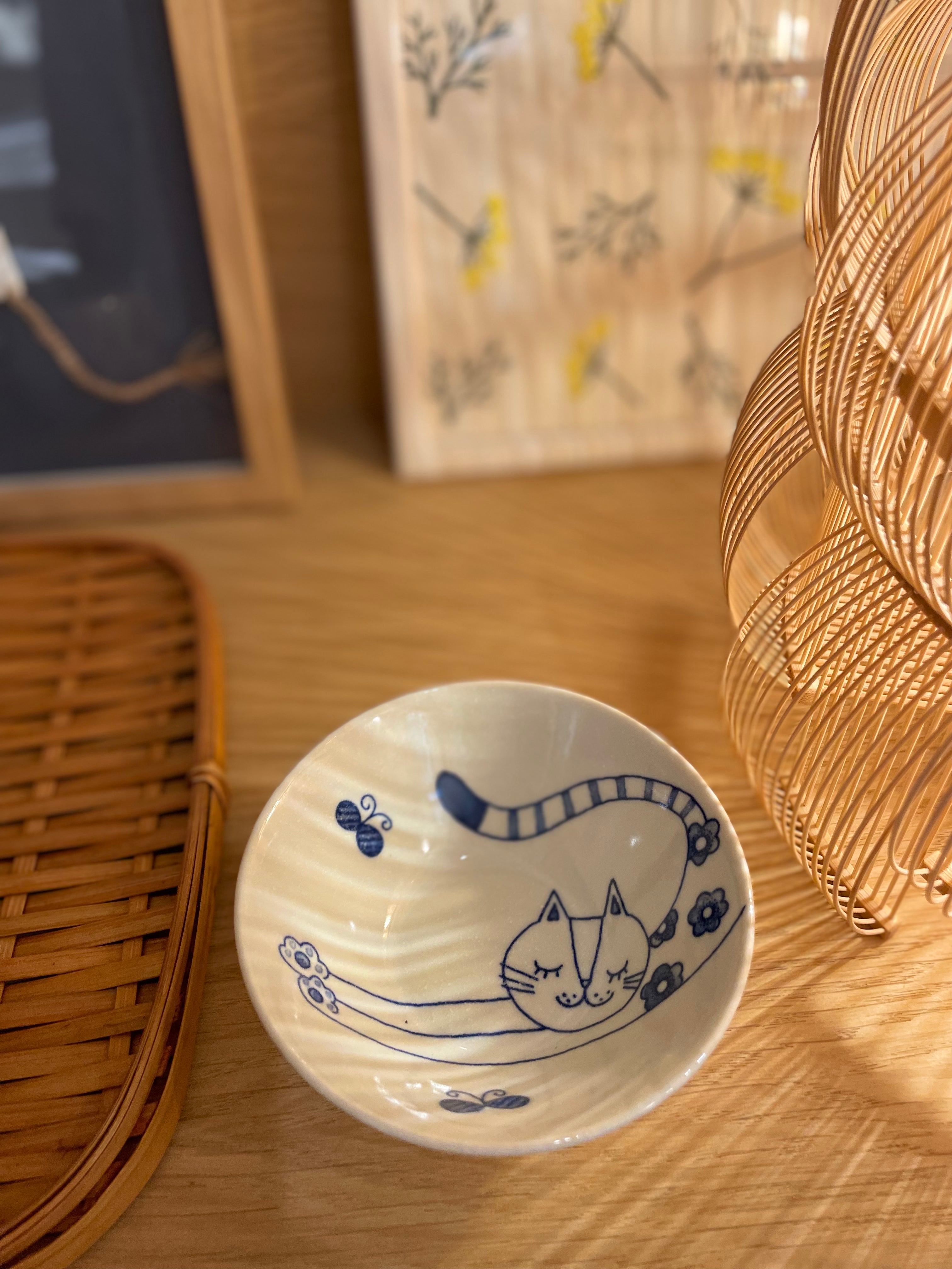 Small white bowl with blue cat stretching