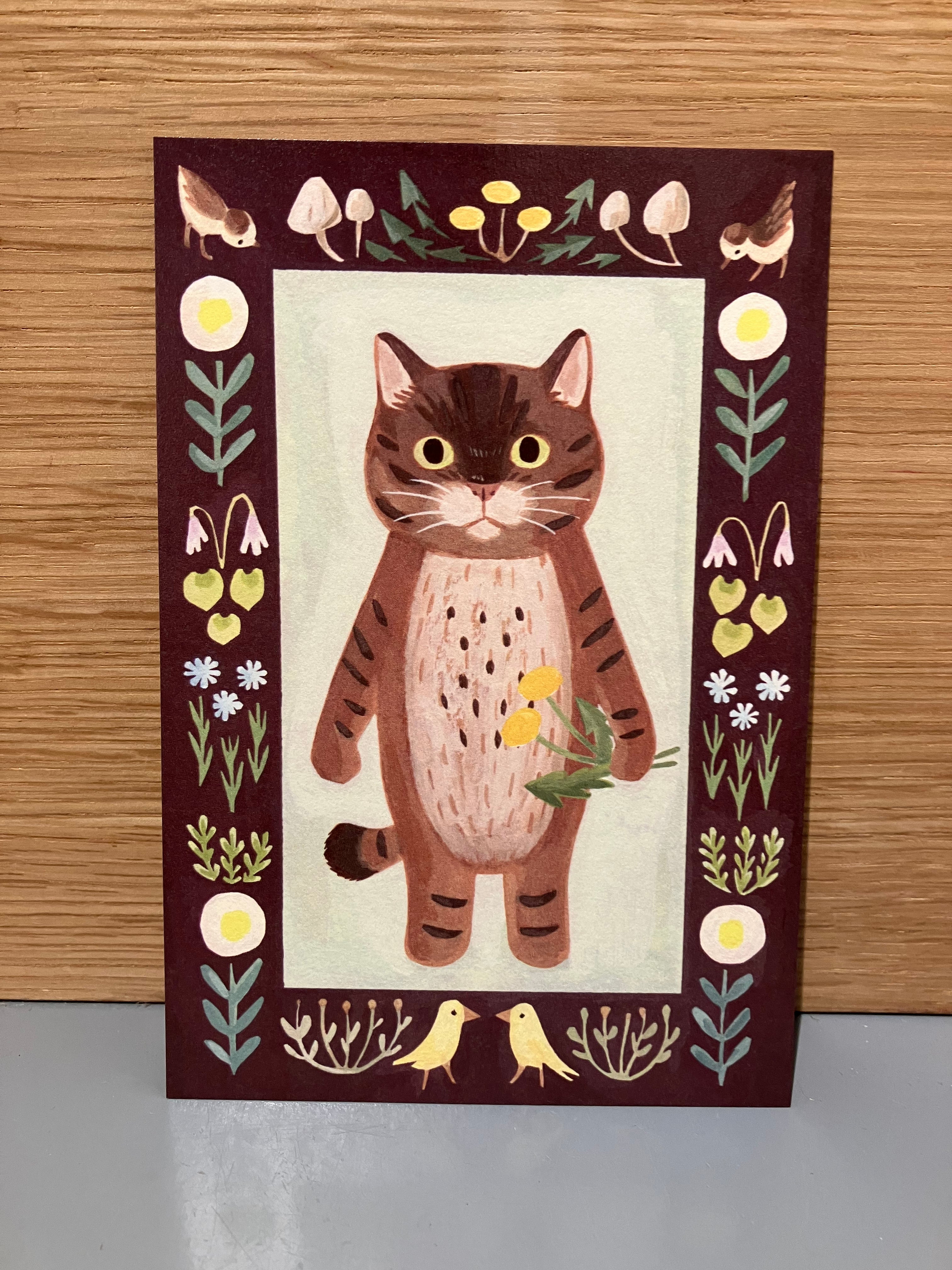 Japanese card with a cat holding a pair of dandelions