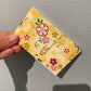 Lille gul notesblok med blomster