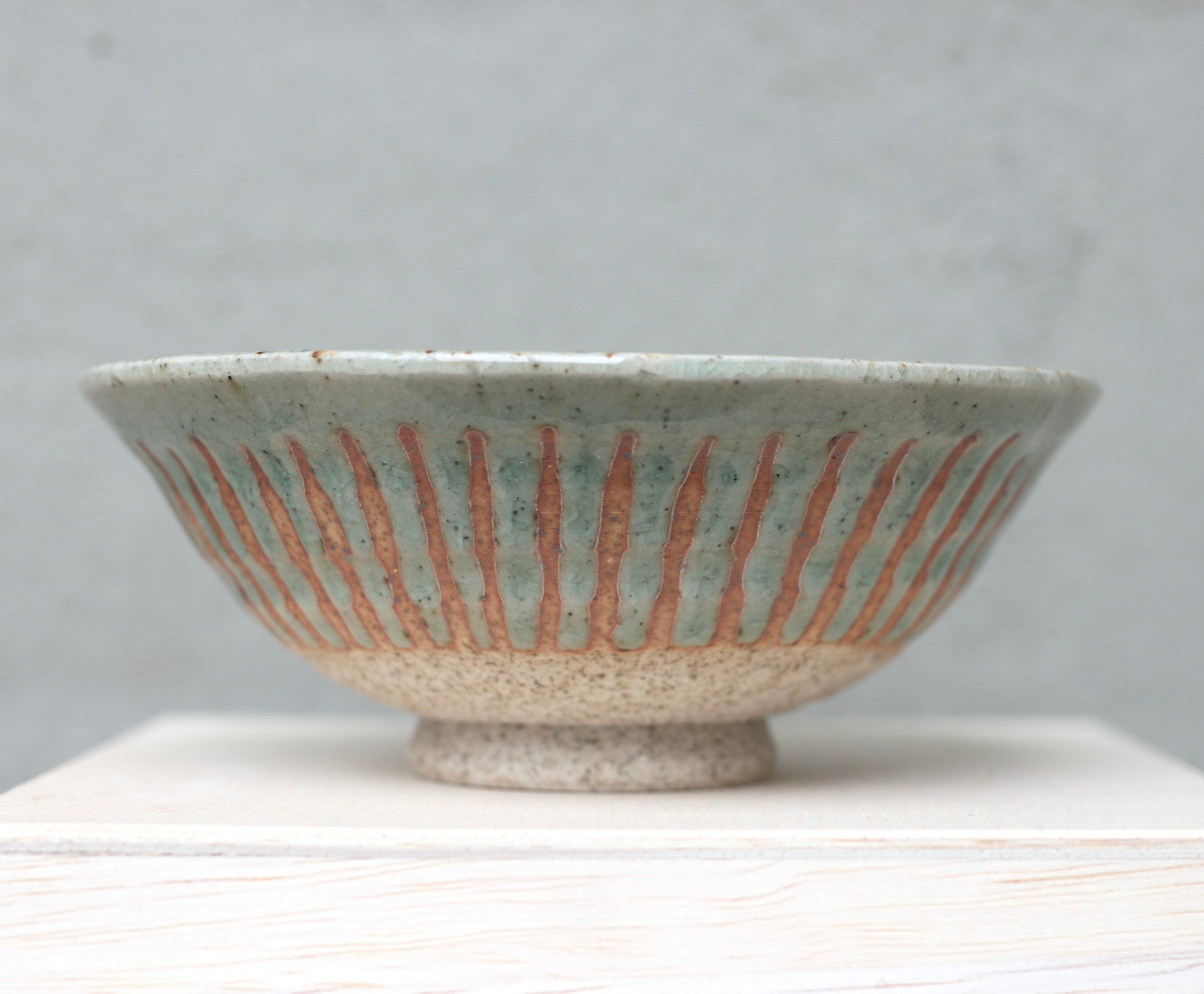 Green-blue ceramic bowl with brownish stripes