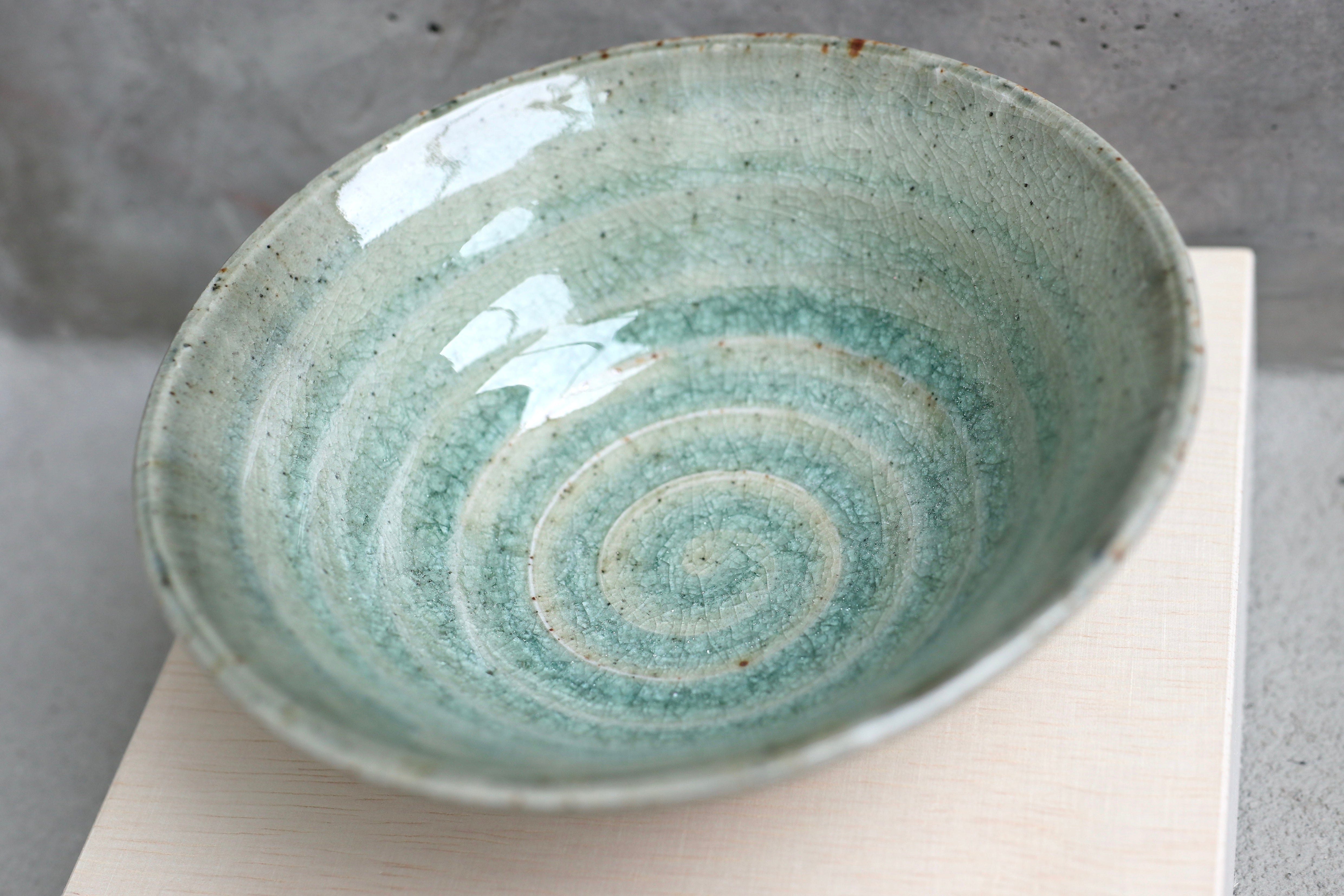 Green-blue ceramic bowl with brownish stripes