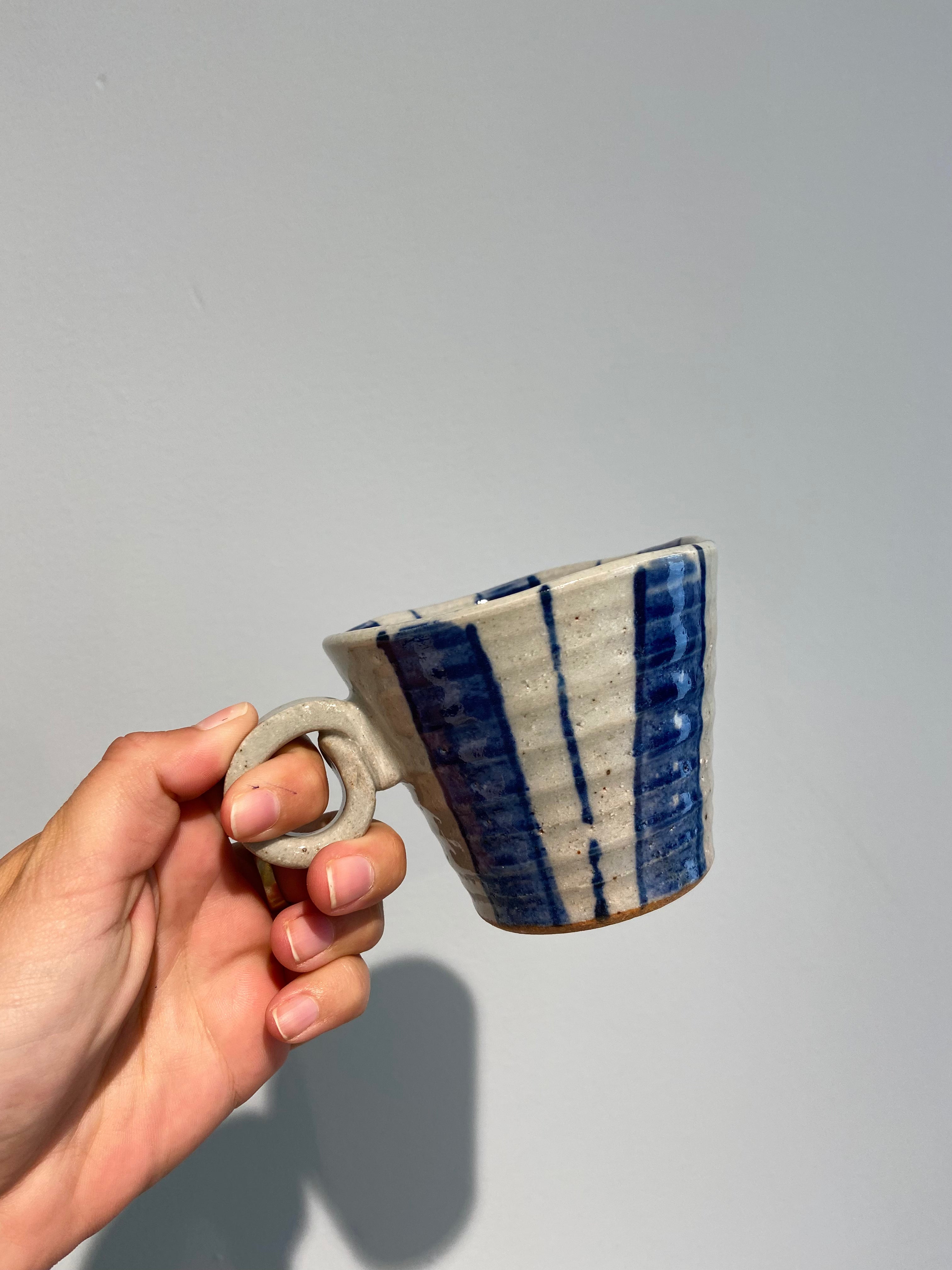 Ceramic cup with wide stripes and round handle