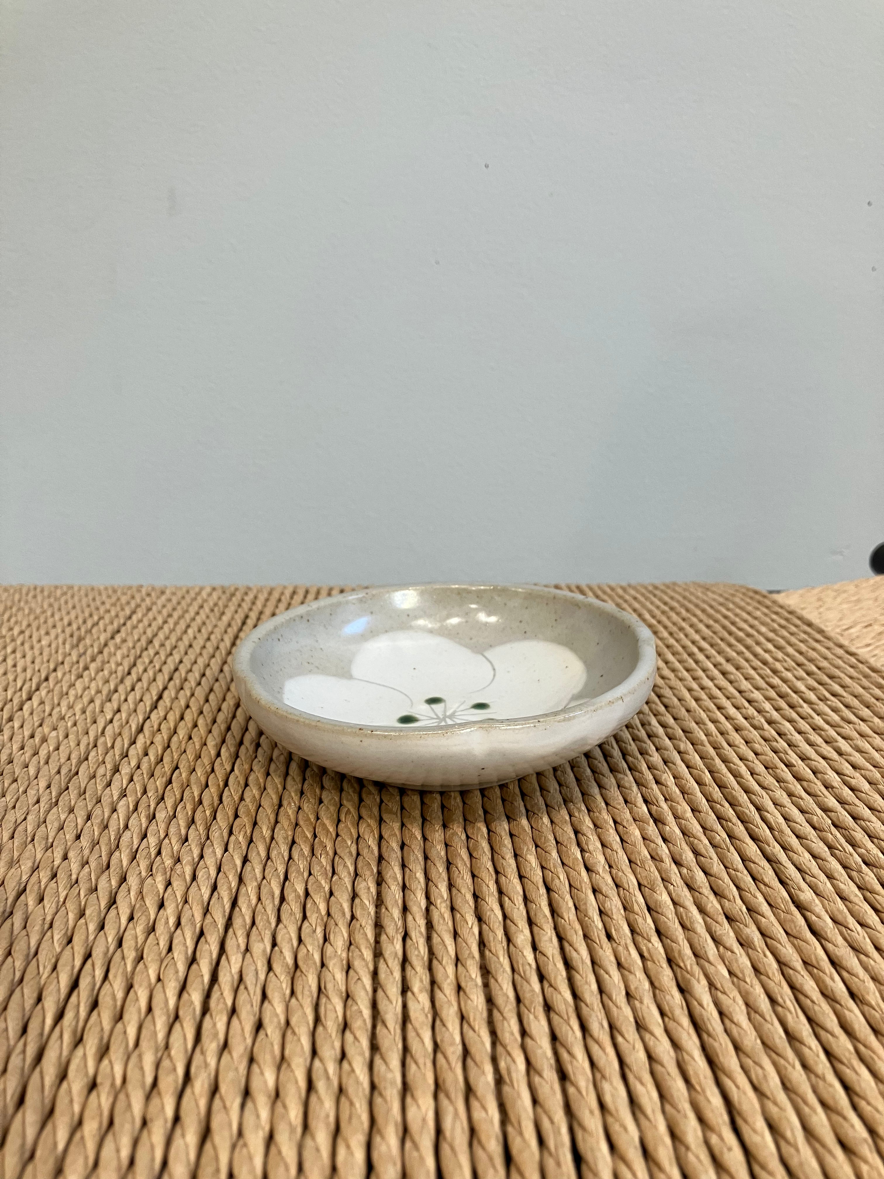 Small gray bowl with white flower and green dots