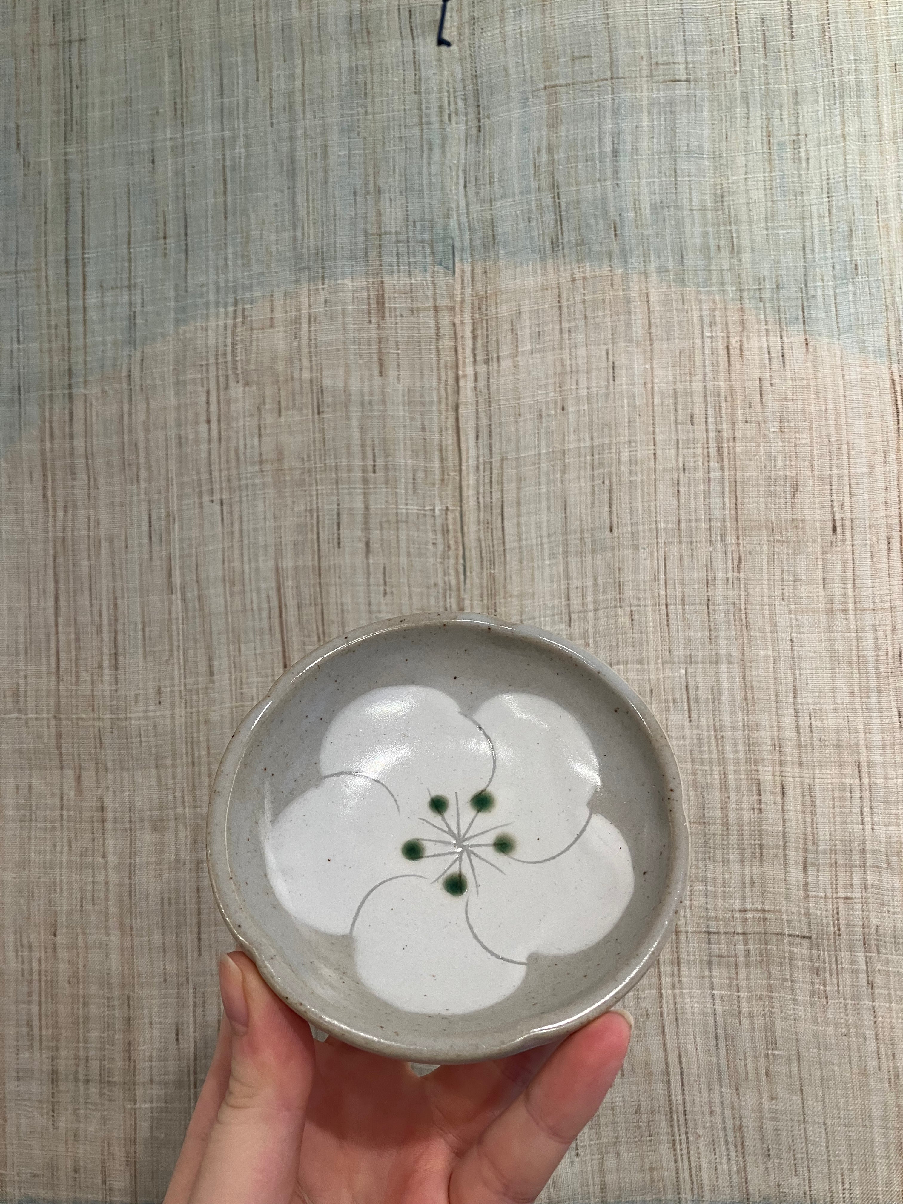 Small gray bowl with white flower and green dots